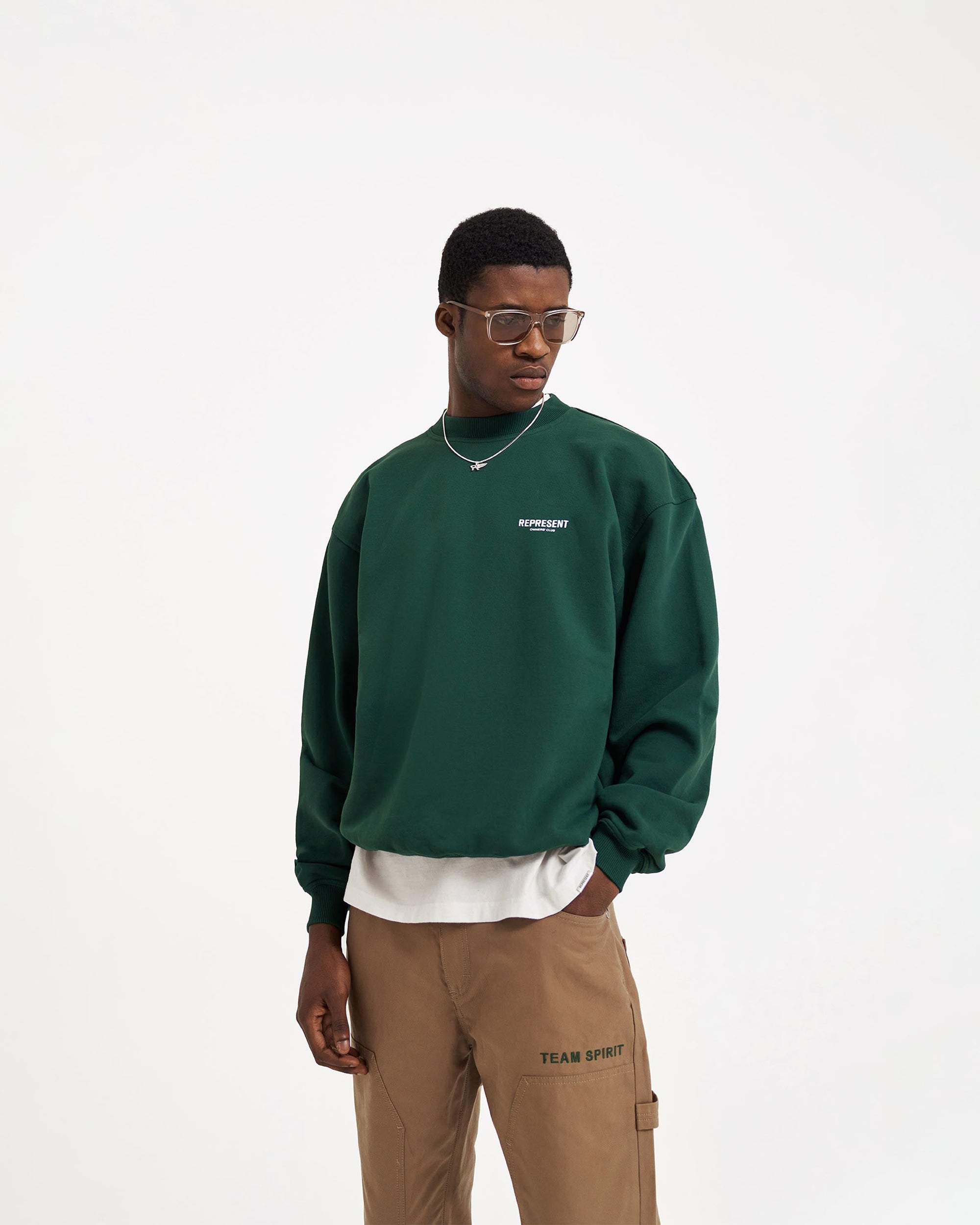 Man wearing a green sweater on a plain white background | Represent Owners Club Sweater in Racing Green | Heavyweight oversized cotton sweater with ribbed trims | Owners Club Sweaters | Represent Clo