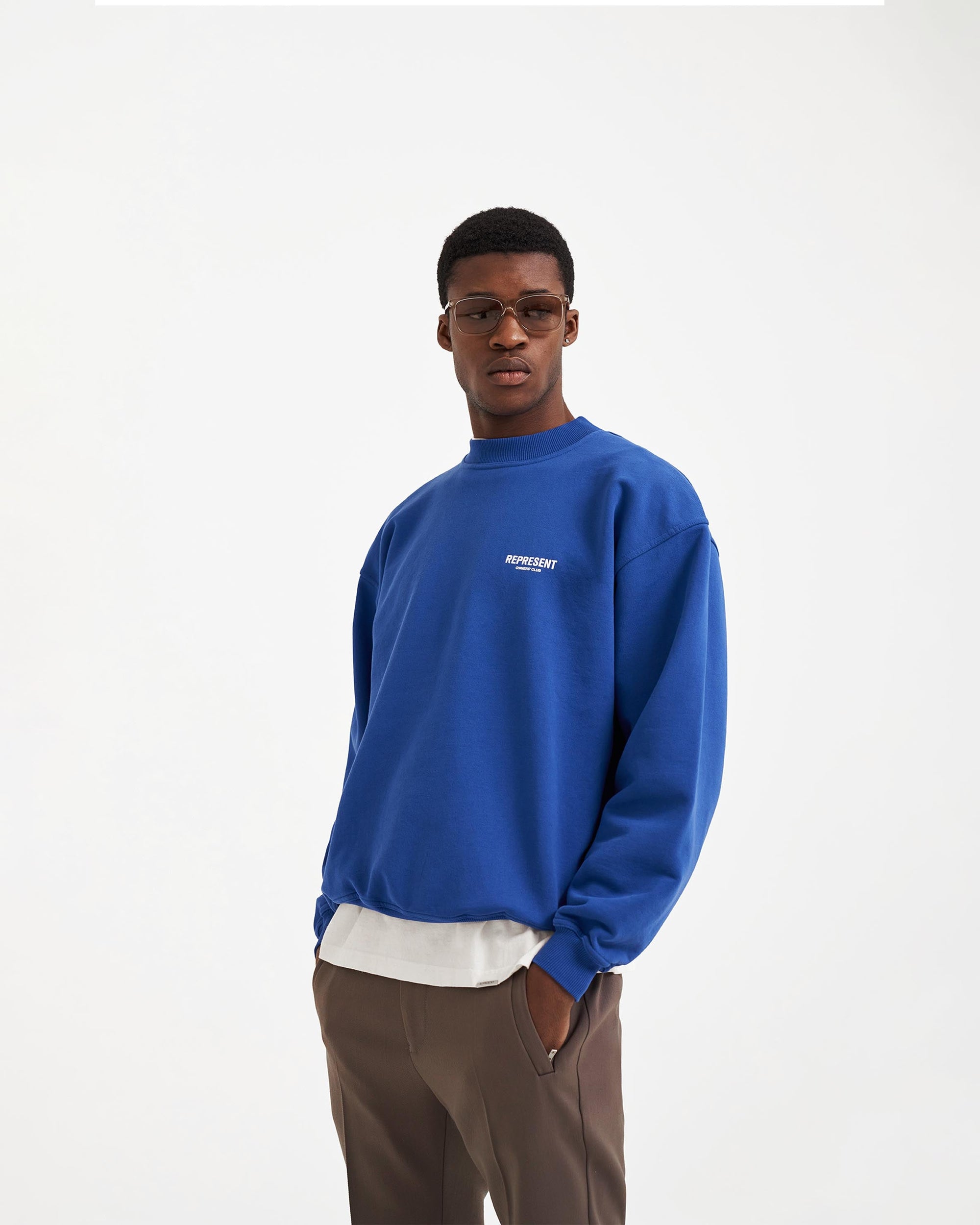 Man wearing a cobalt blue sweater on a plain white background | Represent Owners Club Sweater in Cobalt | Heavy weight jersey sweater with ribbed hem and cuffs | Owners Club Sweaters | Represent Clo