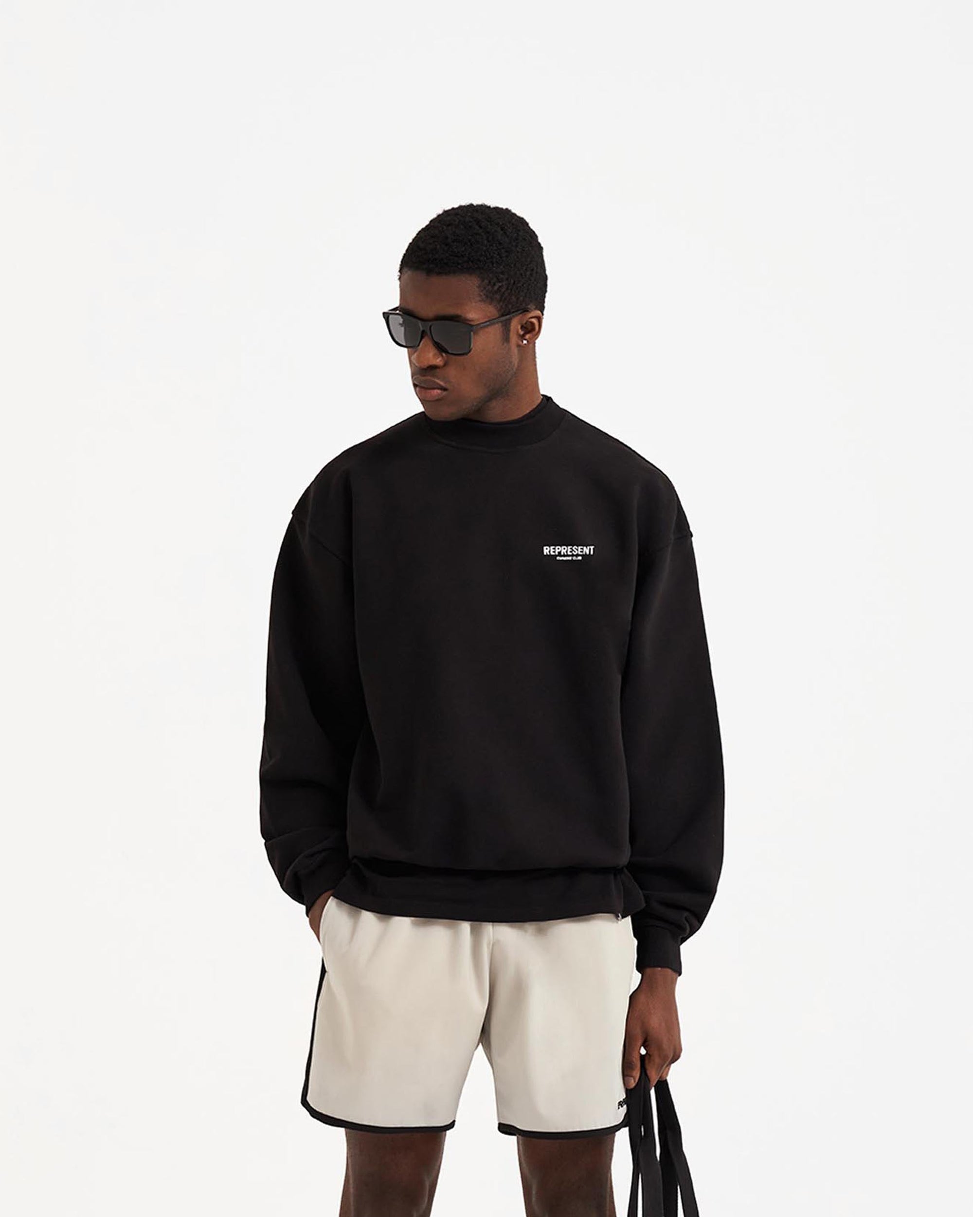 Man wearing an oversized black sweater on a plain white background | Represent Owners Club Sweater in Black | Heavy weight jersey cotton crewneck sweater | Owners Club Sweaters | Represent Clo