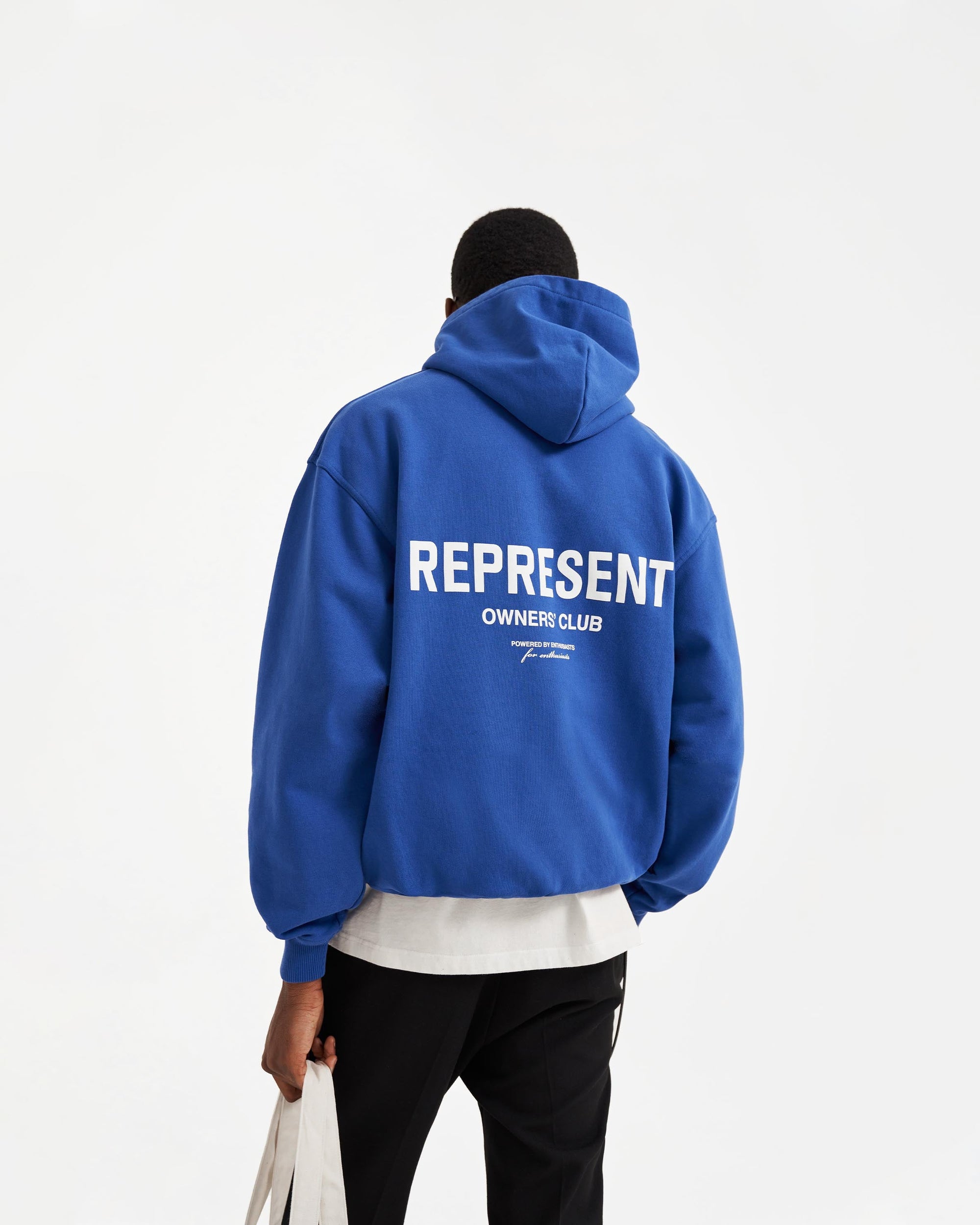 Man wearing an oversized cobalt blue hoodie on a plain white background | Represent Owners Club Hoodie in Cobalt | Heavy weight oversized fit with Owners Club print | Owners Club Hoodies | Represent Clo