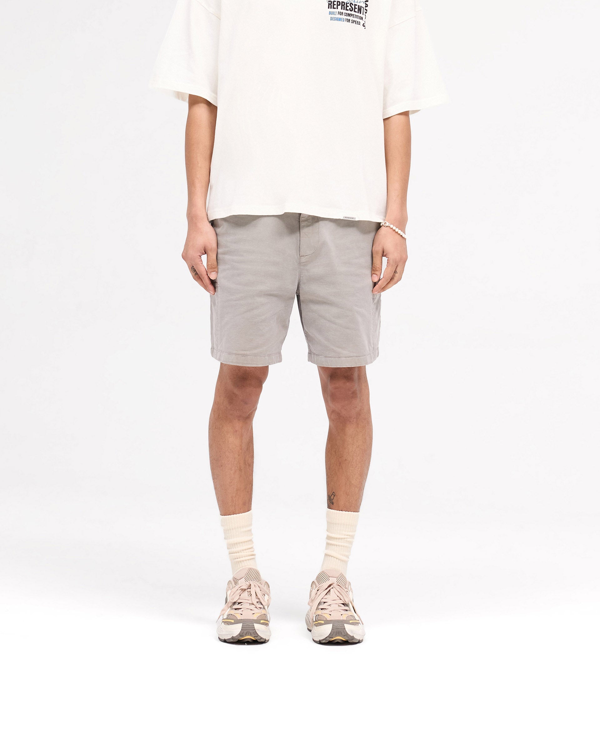 Man wearing a taupe cargo shorts on a plain white background | Season Cargo Short in Washed Taupe | Shorts with welt cargo and diagonal pockets | SS25 Shorts | Represent Clo