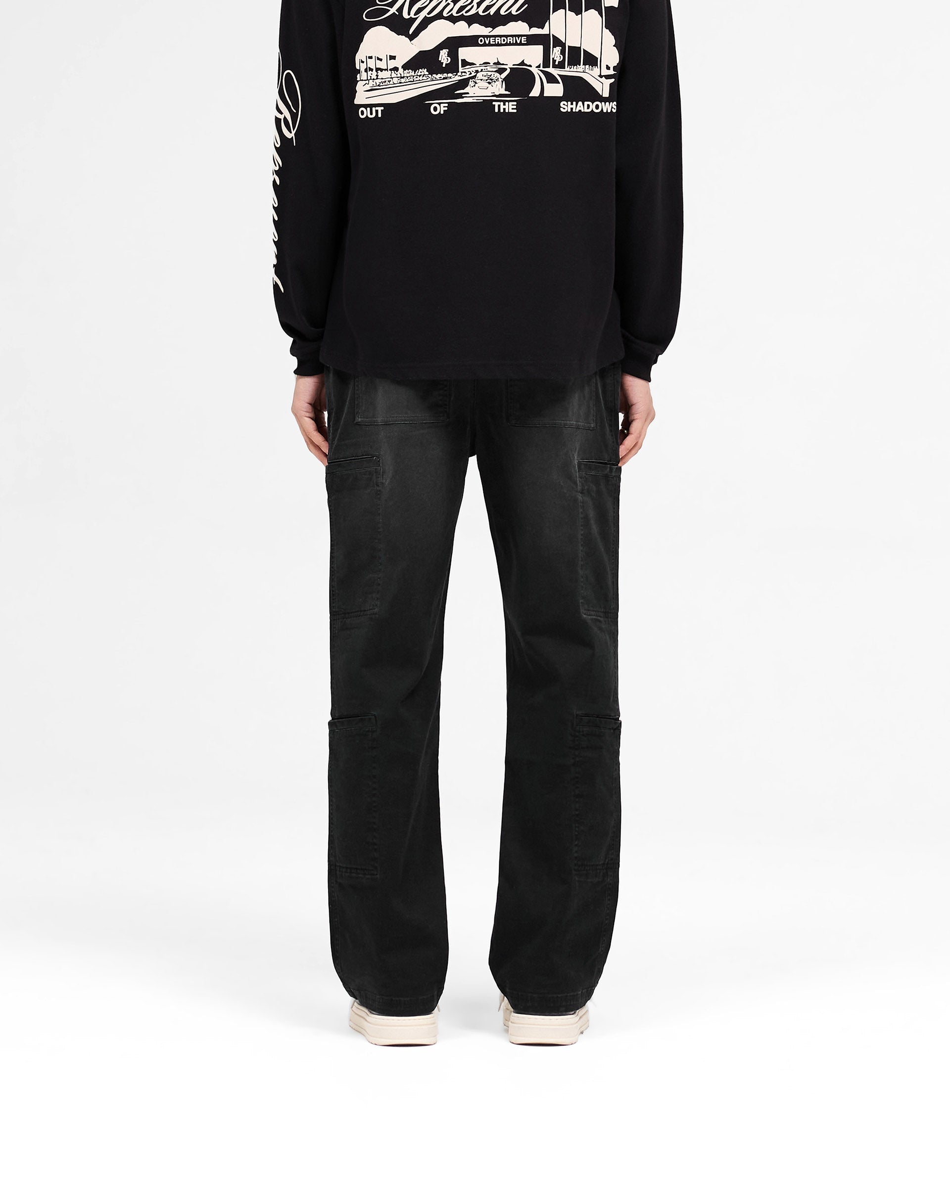 Man wearing black cargo pants on a plain white background | Season Cargo Pant in Jet Black | Relaxed fit cargo pants with brushed twill fabric | SS25 Pants | Represent Clo