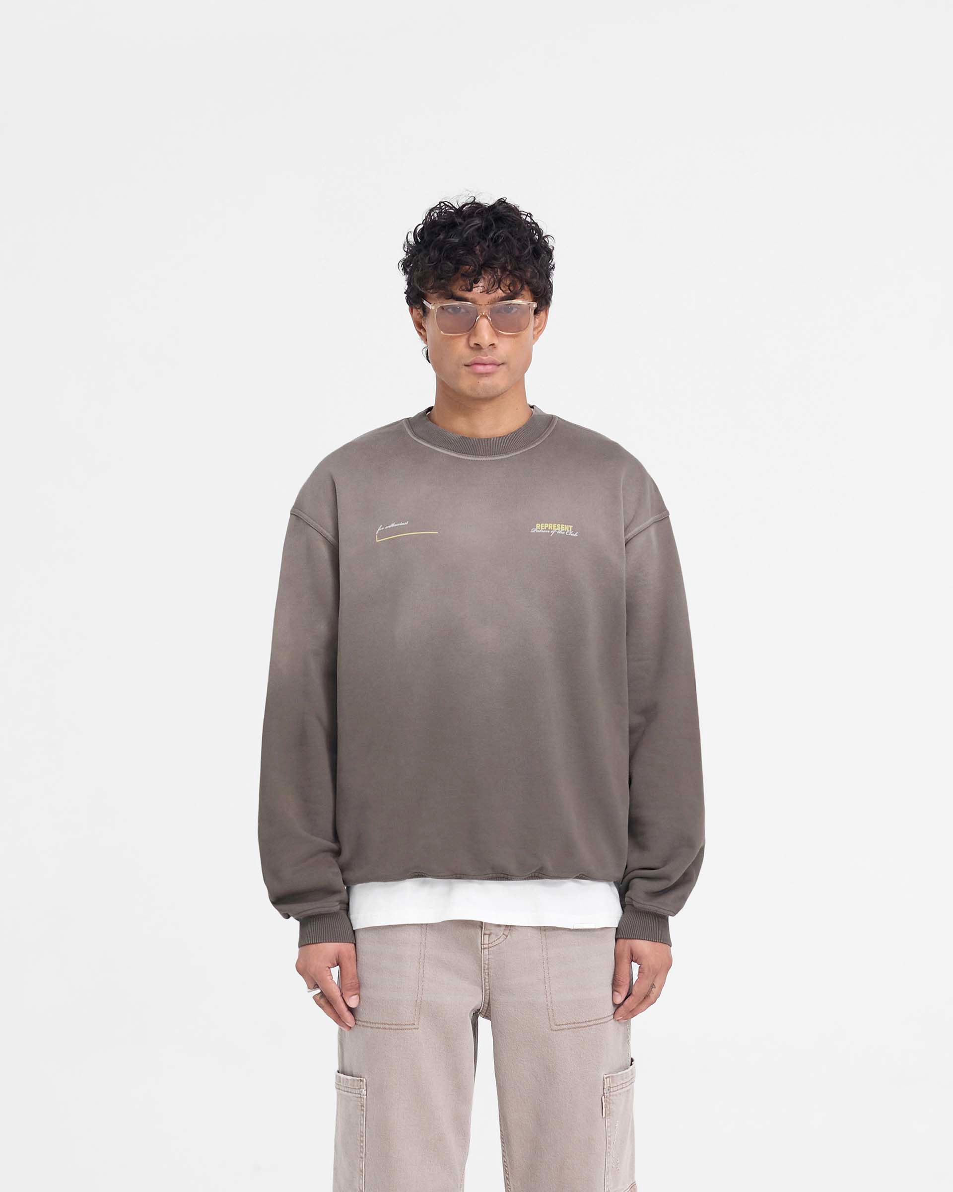 Man wearing an oversized olive sweater on a plain white background | Patron Of The Club Sweater in Washed Olive | Oversized fit luxury sweater with Patron of the Club print | Patrons Sweaters | Represent Clo