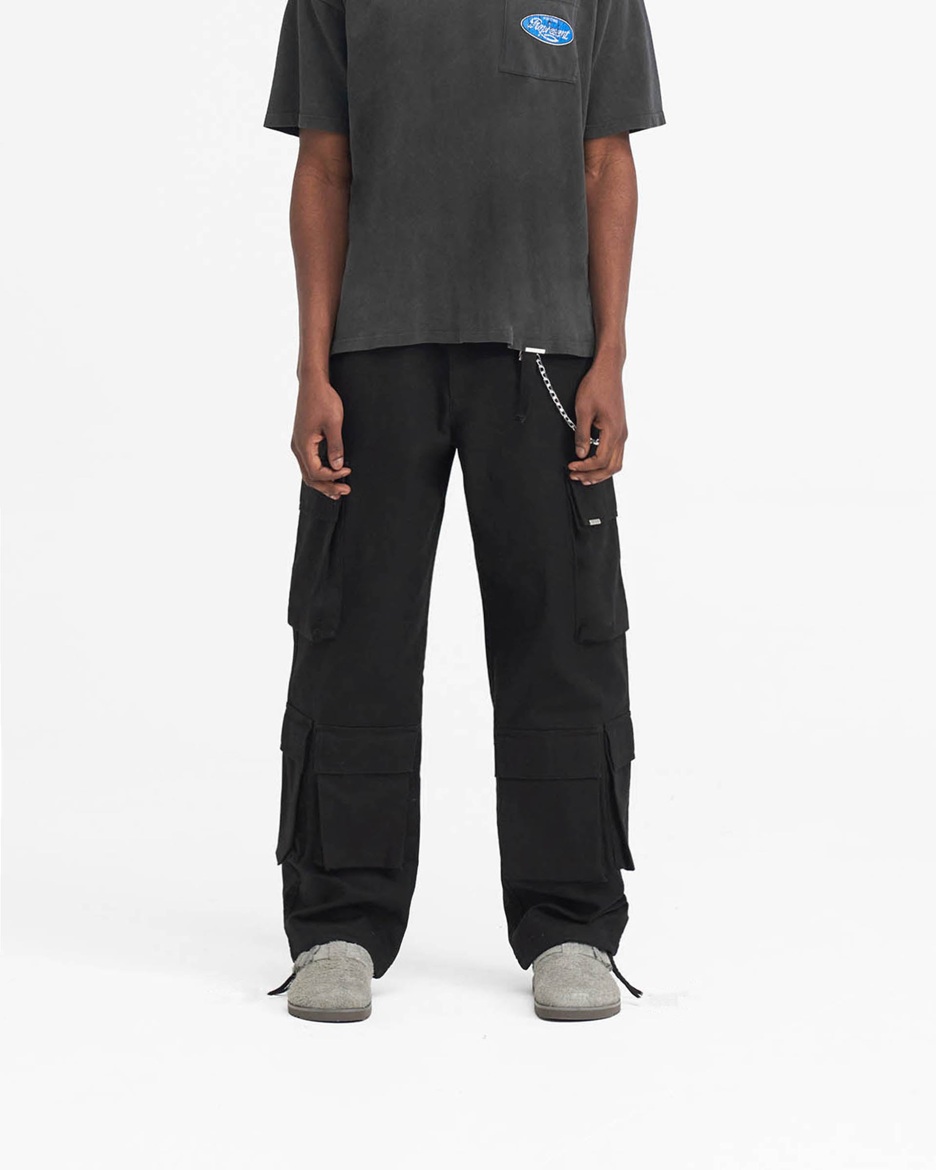 Man wearing black baggy cargo pants on a plain white background | Baggy Cargo Pant in Black | Pants with 3D oversized pockets | SS24 Pants | Represent Clo