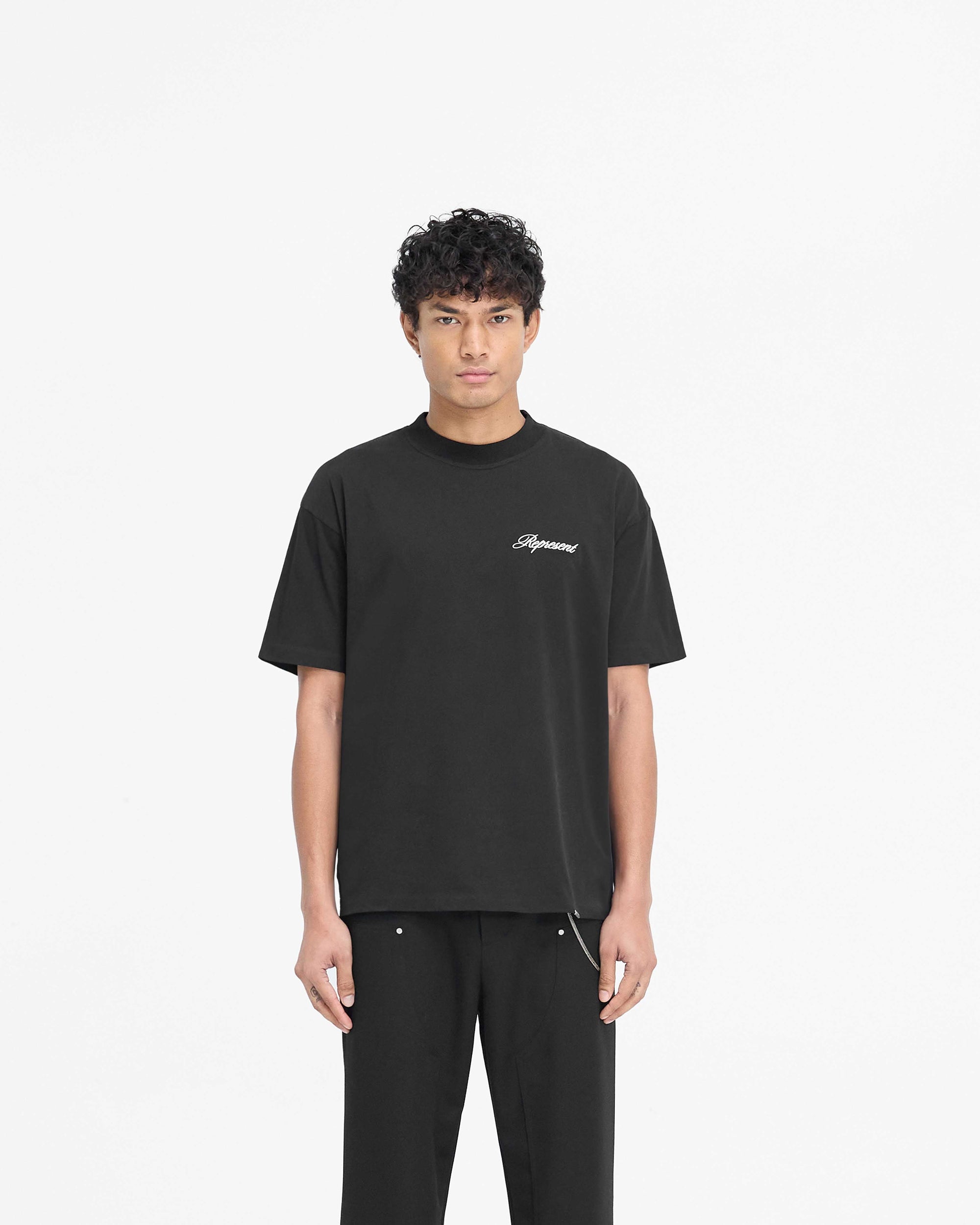 Man wearing a black t-shirt on a plain white background | Script Logo T-Shirt in Black | Slightly oversized t-shirt with high build embroidery | PRE SS25 T-Shirts | Represent Clo