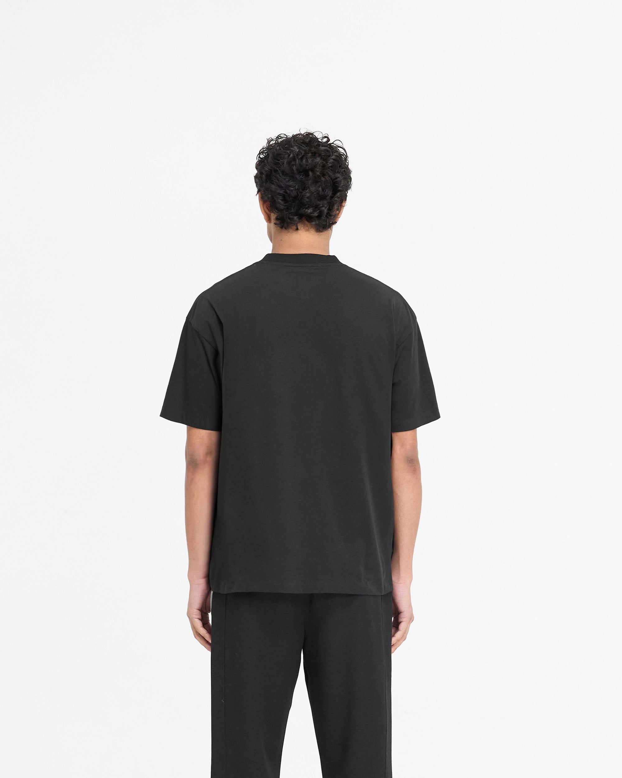 Man wearing a black t-shirt on a plain white background | Script Logo T-Shirt in Black | Slightly oversized t-shirt with high build embroidered script branding | PRE SS25 T-Shirts | Represent Clo