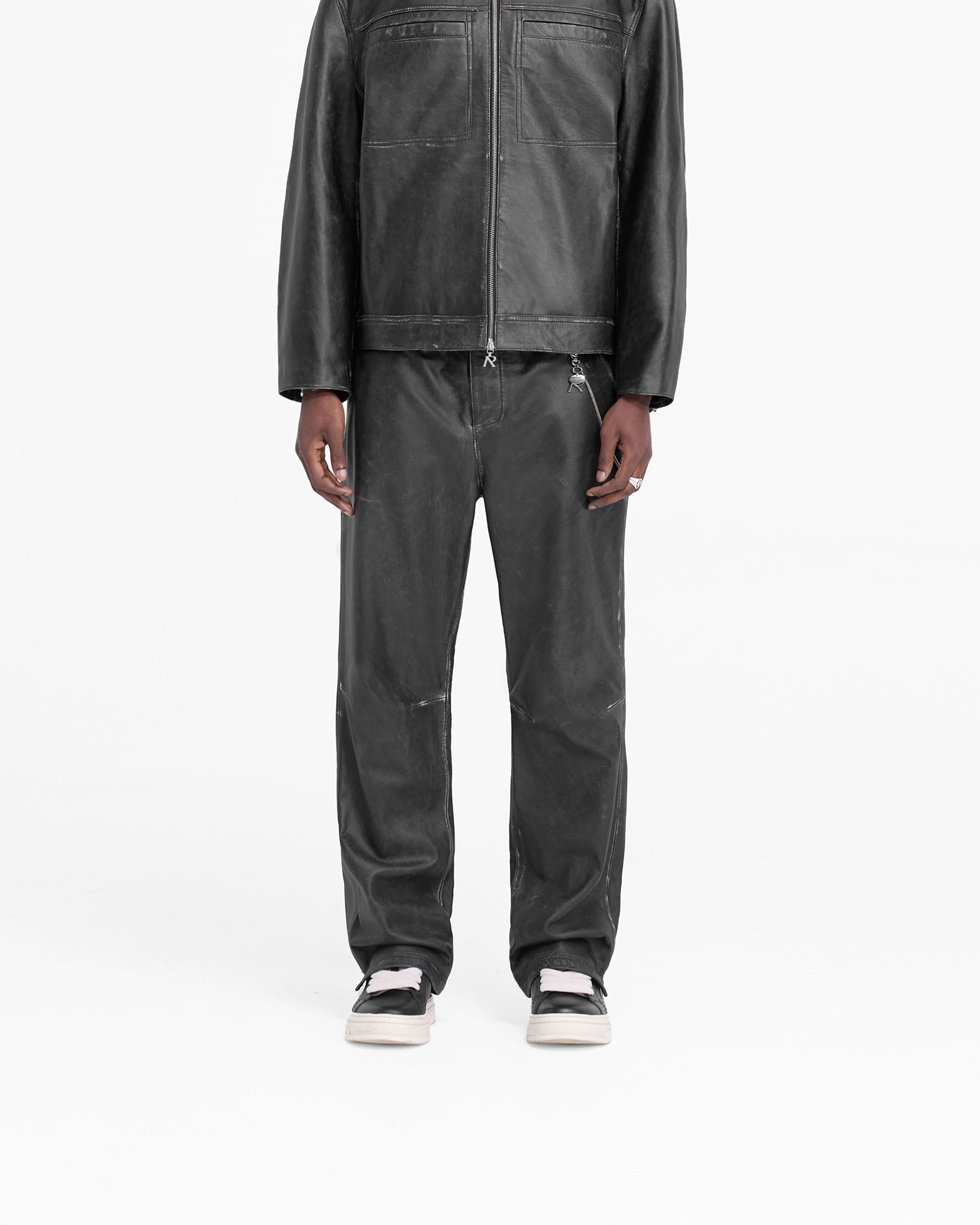 Man wearing black leather pants on a plain white background | Distressed Leather Pant in Black | Hand distressed wide straight leg leather pants | FW24 Pants | Represent Clo