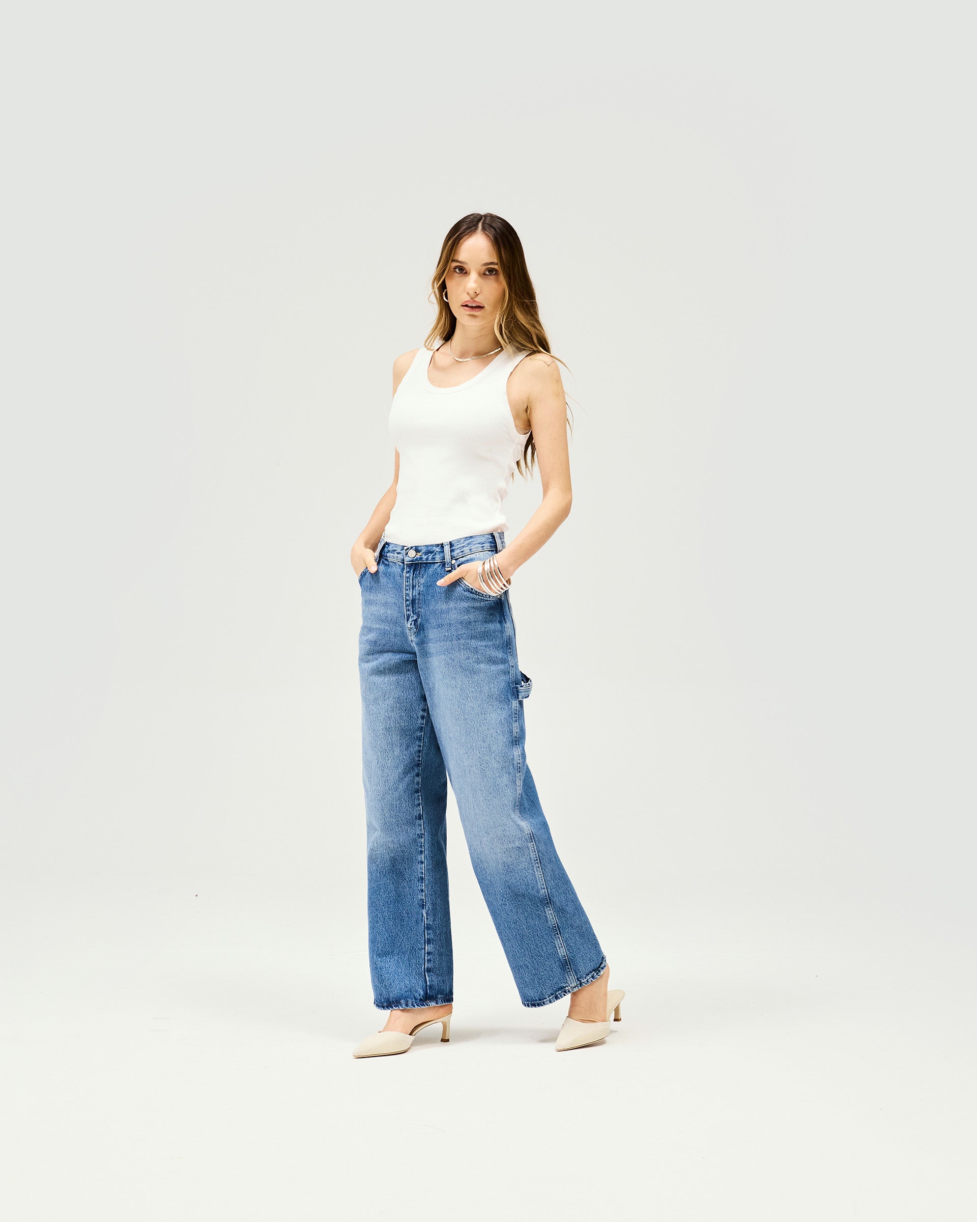 Woman wearing very oversized washed blue jeans on a plain white background | Skater Jean in Washed Blue | Low rise jeans with skater back pockets and triple needle stitching | Womens SS25 Jeans | Represent Clo