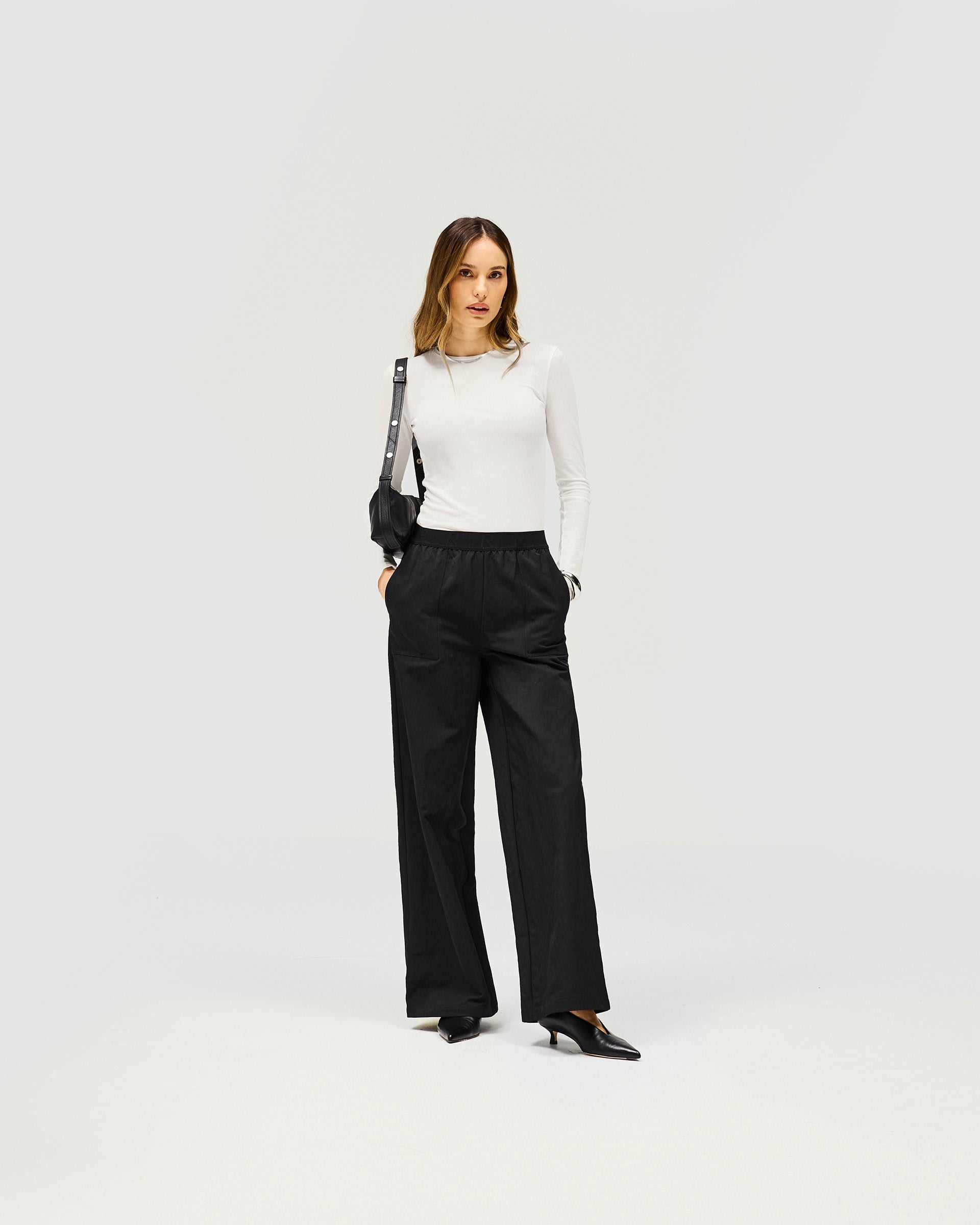 Woman wearing black jogger pants on a plain white background | Subway Jogger in Jet Black | Lightweight crinkle textured nylon jogger | Womens SS25 Bottoms | Represent Clo