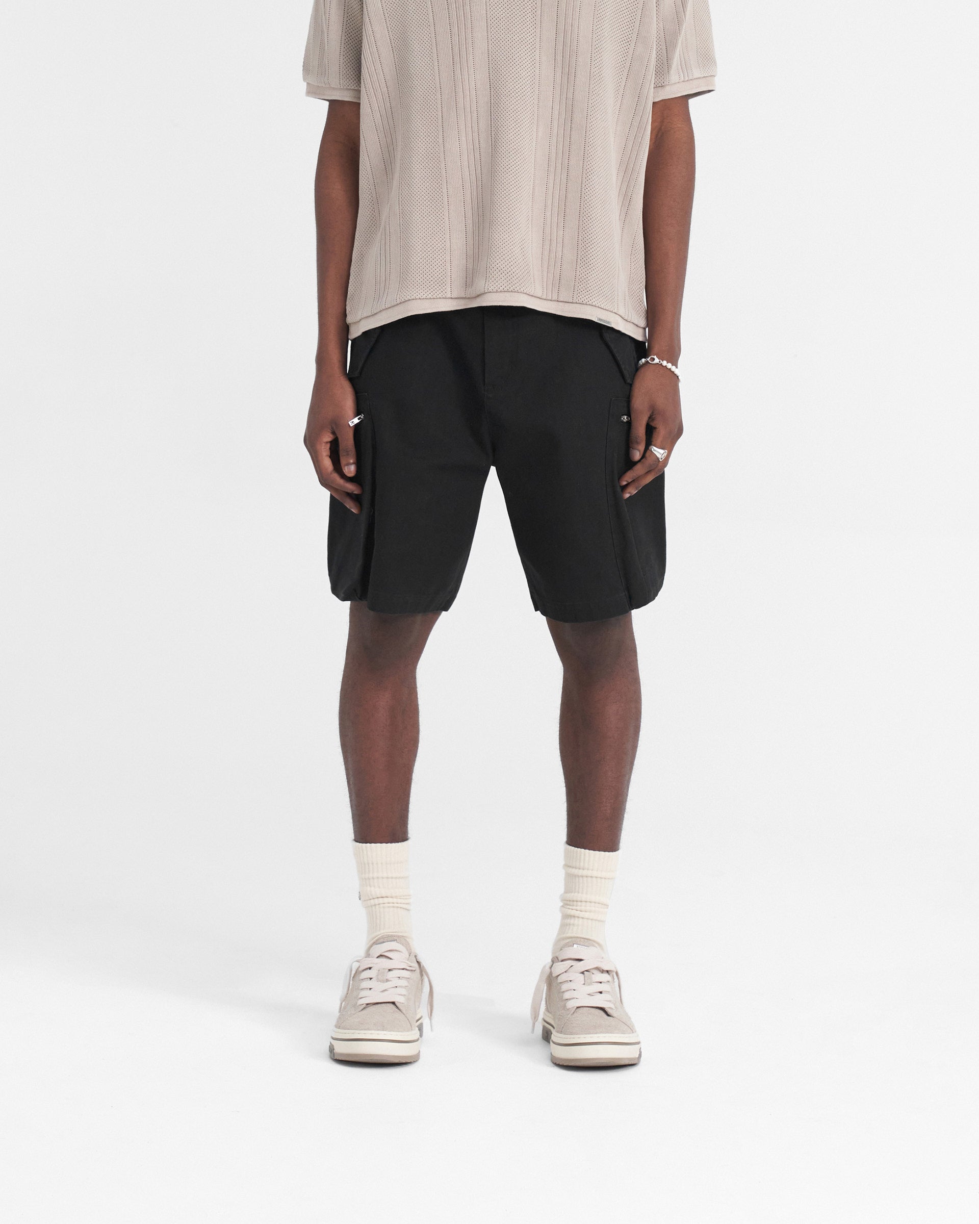 Man wearing black baggy fit shorts on a plain white background | Workshop Short in Black | Shorts with cargo and 3D back pockets | SS24 Shorts | Represent Clo