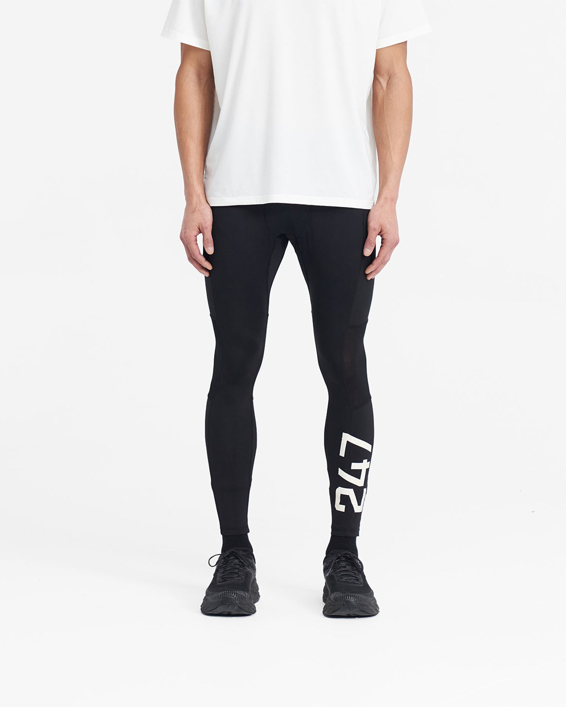 Man wearing black running tights on a plain white background | 247 Run Tight in Jet Black | Running tights with ripstop and mesh panels | 247 Pants | Represent Clo