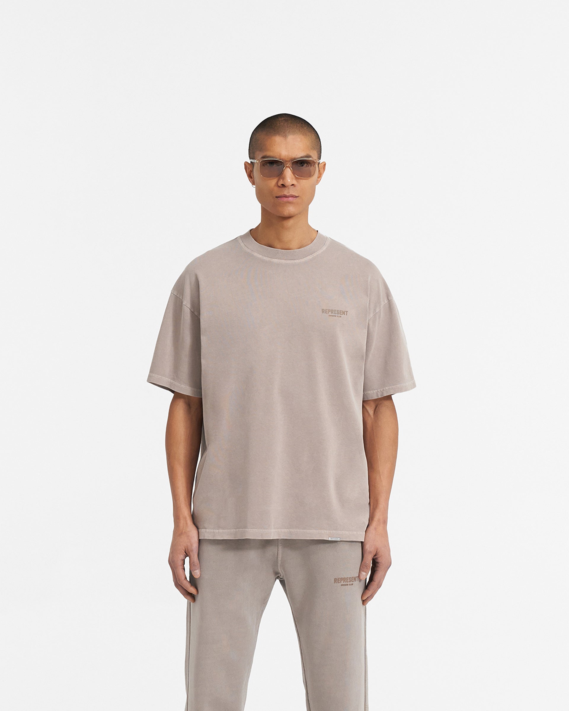 Man wearing a grey t-shirt on a plain white background | Represent Owners Club T-Shirt in Mushroom | Short sleeve jersey tee with high build branding | Owners Club T-Shirts | Represent Clo