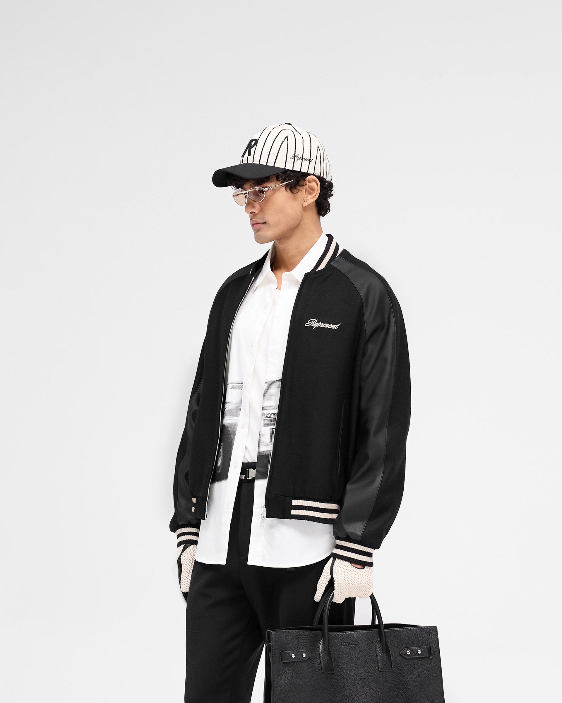 Back product image of a mens black jacket on a plain white background | Raglan Varsity Jacket in Black | Jacket with raglan PU sleeves and zip pockets | SS25 Outerwear | Represent Clo