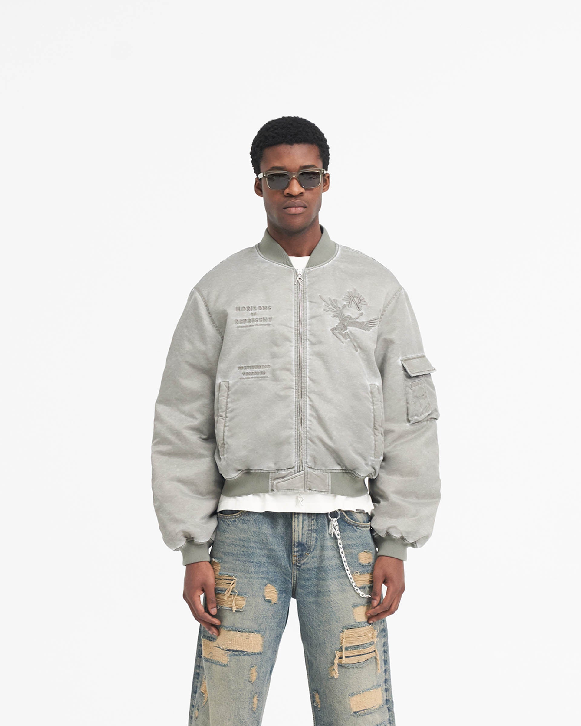 Man wearing a khaki bomber jacket on a plain white background | Icarus Flight Bomber in Khaki | Bomber jacket with sleeve gathering and pendant zip | SS24 Outerwear | Represent Clo