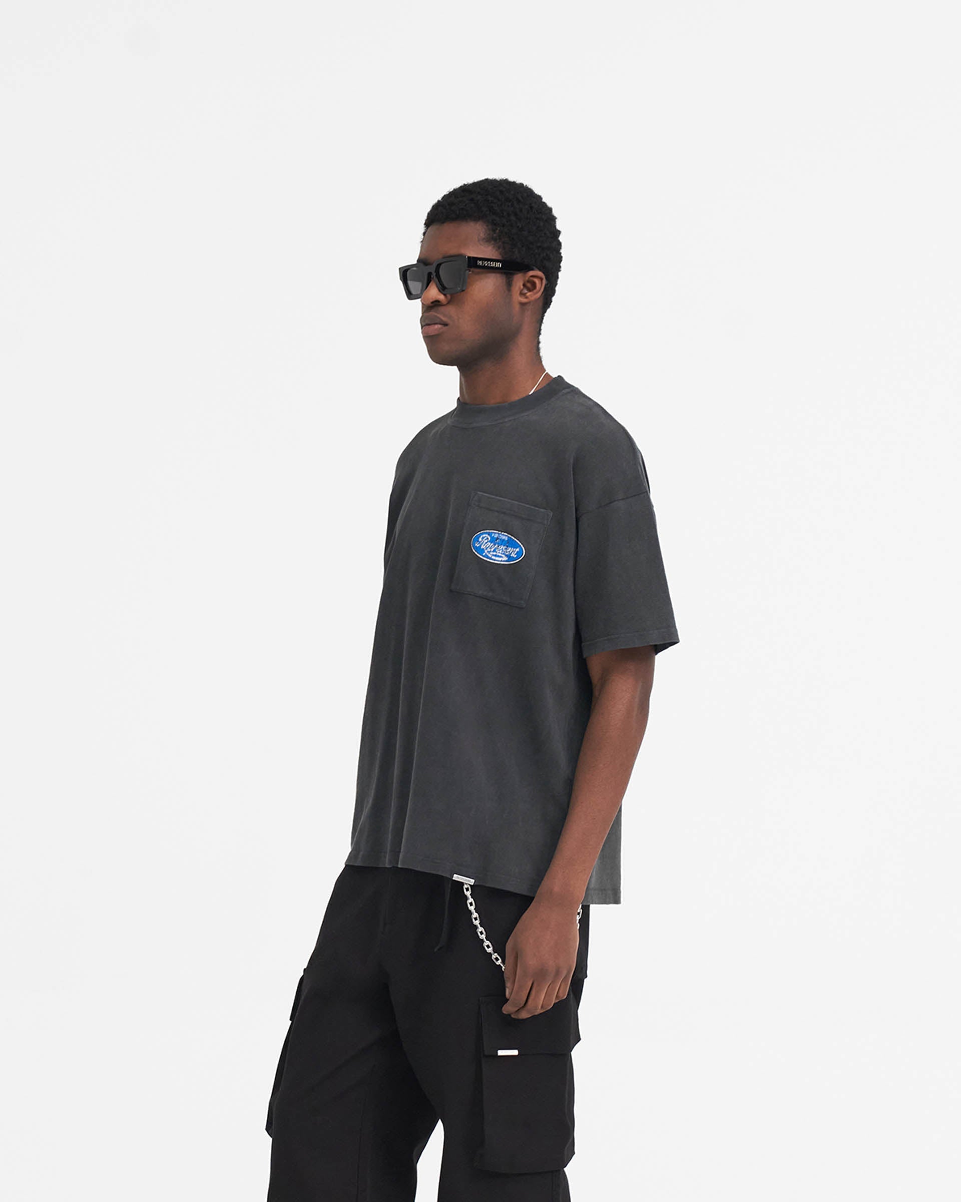 Man wearing an aged black t-shirt on a plain white background | Classic Parts T-Shirt in Aged Black | Oversized fit t-shirt with motorsport graphic | SS24 T-Shirts | Represent Clo