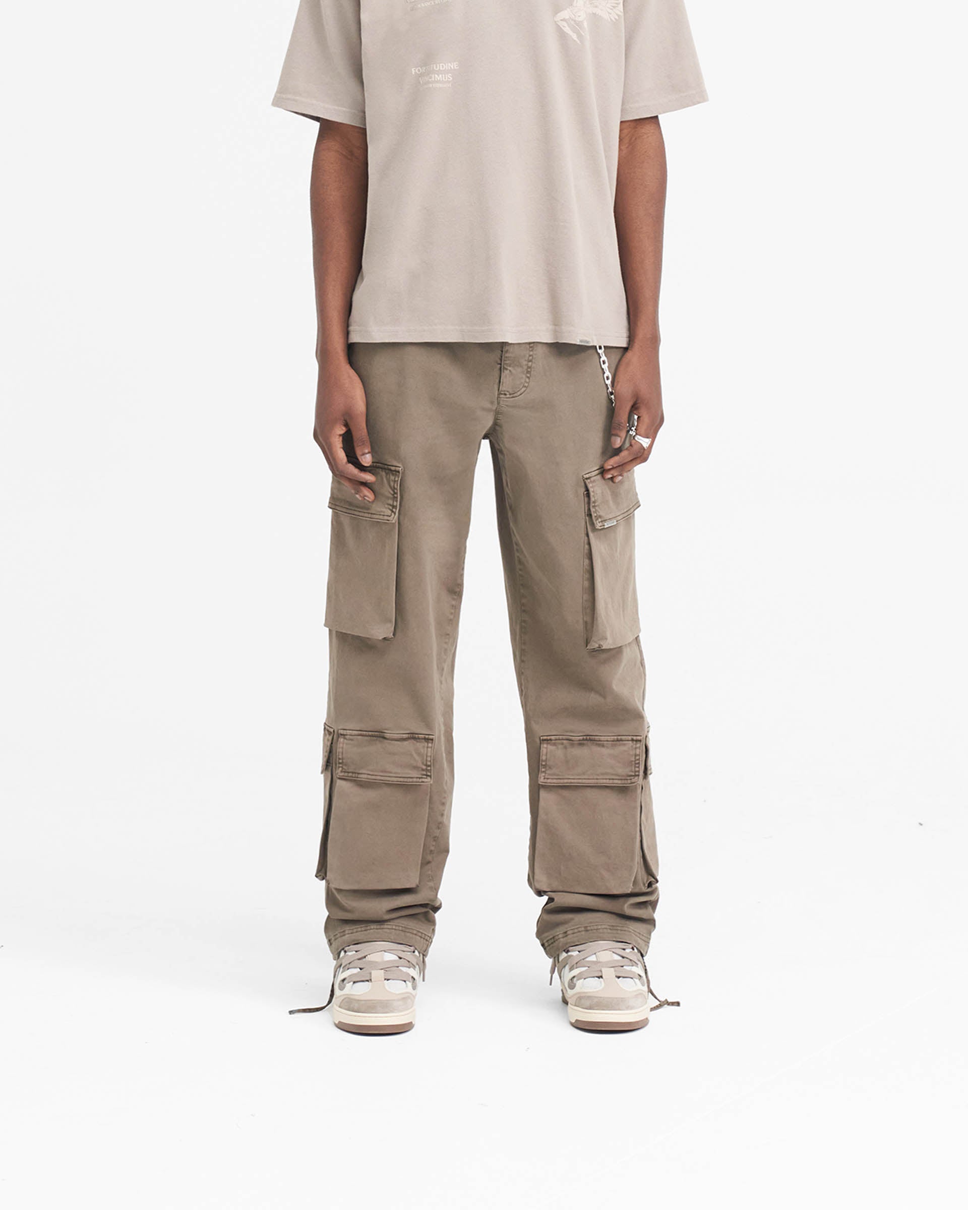 Man wearing baggy grey cargo pants on a plain white background | Baggy Cargo Pant in Dawn | Luxury cargo pants with oversized 3D pockets | SS24 Pants | Represent Clo