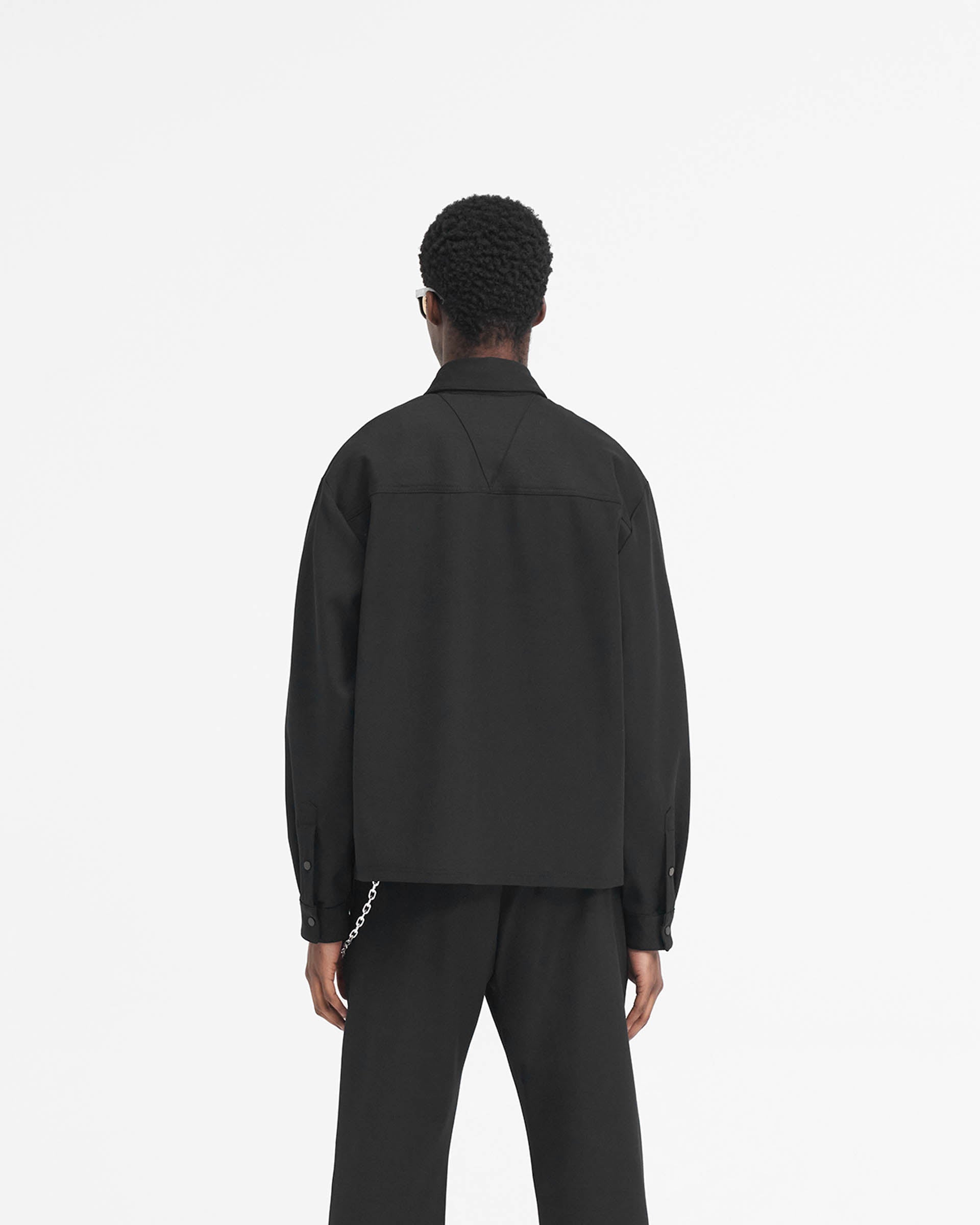 Man wearing a black dress shirt on a plain white background | Initial Cropped Dress Shirt in Black | Virgin wool blend dress shirt with high build logo | SS24 Shirts | Represent Clo