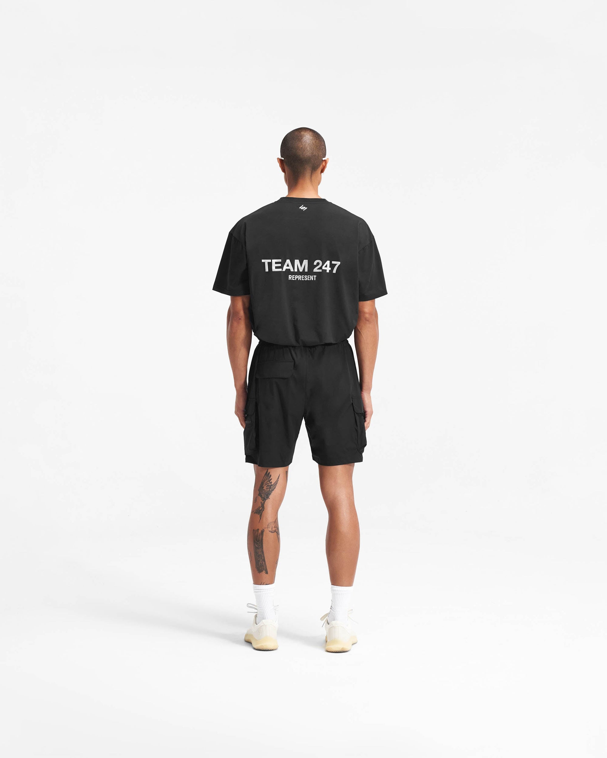 Man wearing black shorts on a plain white background | 247 Shorts in Black | Mens combat shorts with cargo leg pockets and zip side pockets | 247 Shorts | Represent Clo