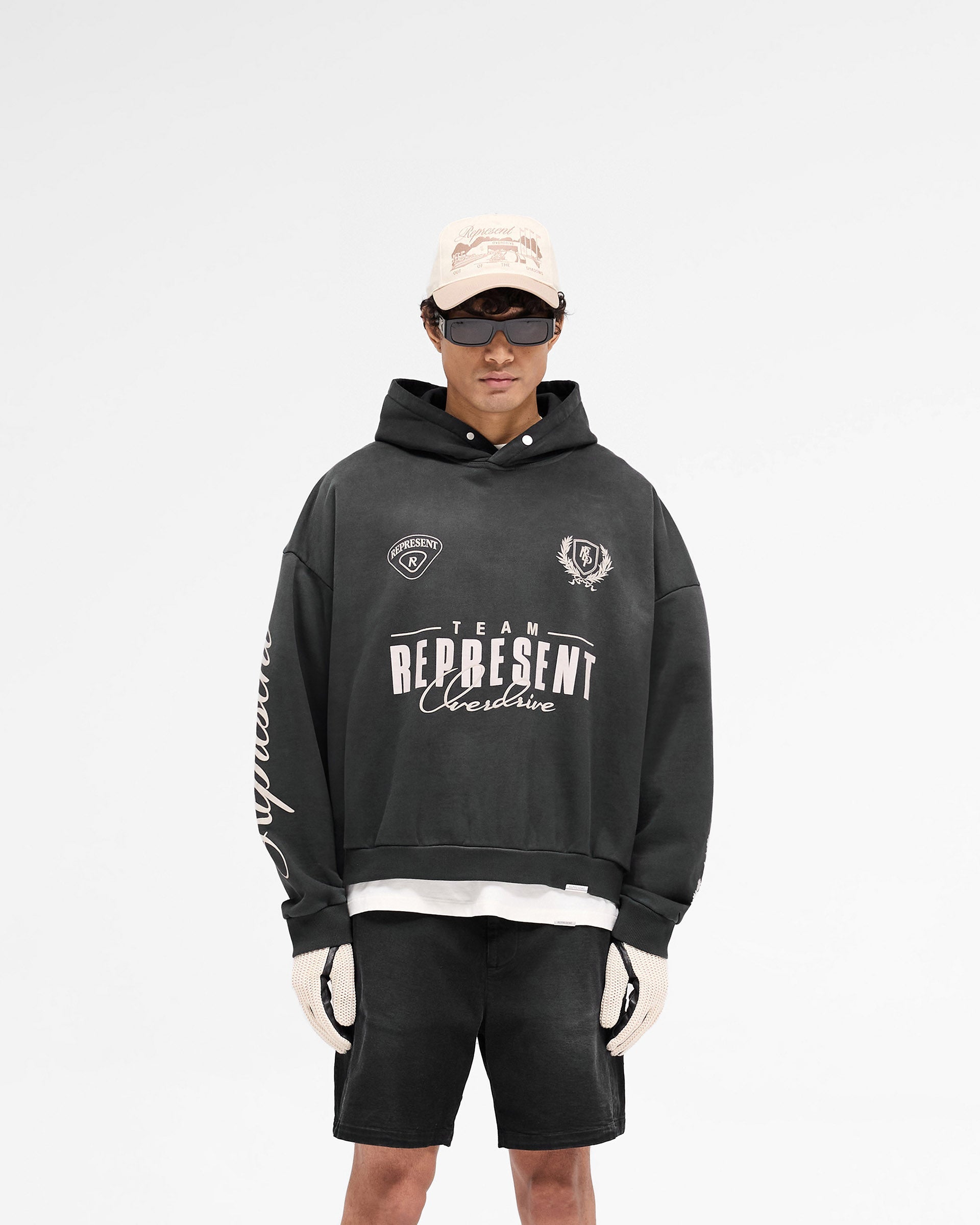 Man wearing an oversized black hoodie on a plain white background | World Championship Hoodie in Stained Black | Boxy fit with screen and puff print graphics | SS25 Hoodies | Represent Clo