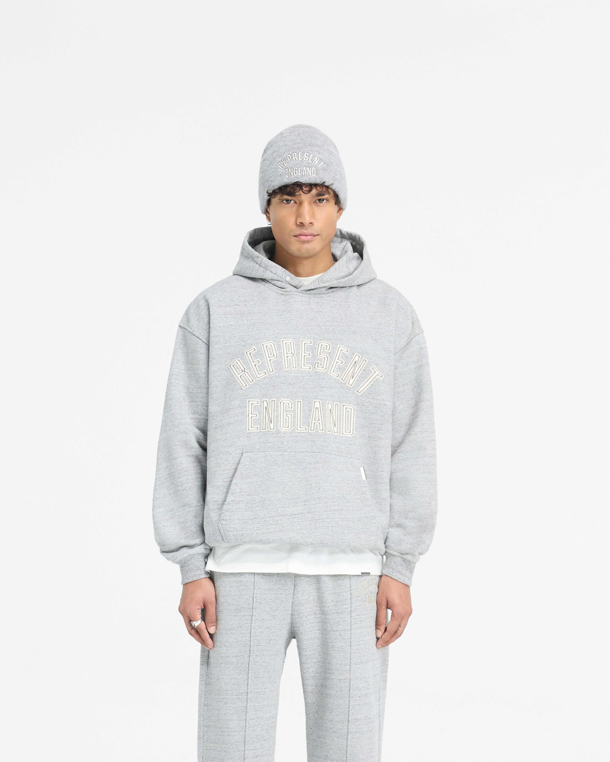 Man wearing a grey hoodie on a plain white background | England Applique Hoodie in Grey Marl | Slightly oversized hoodie with applique embroidery | PRE SS25 Hoodies | Represent Clo