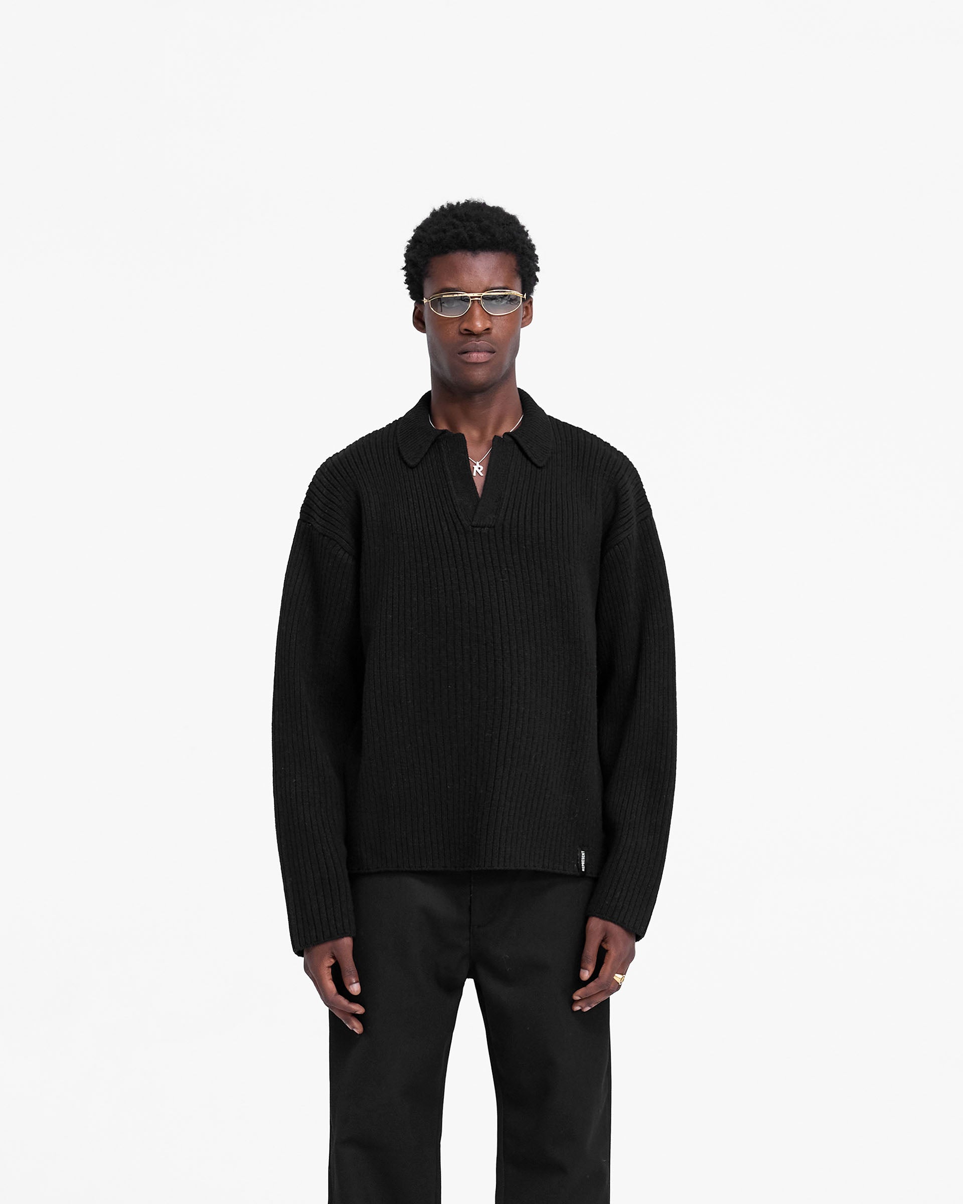 Man wearing a black ribbed knit polo on a plain white background | Ribbed Knit Polo in Jet Black | Wool blend open neck knitwear | FW24 Knitwear | Represent Clo