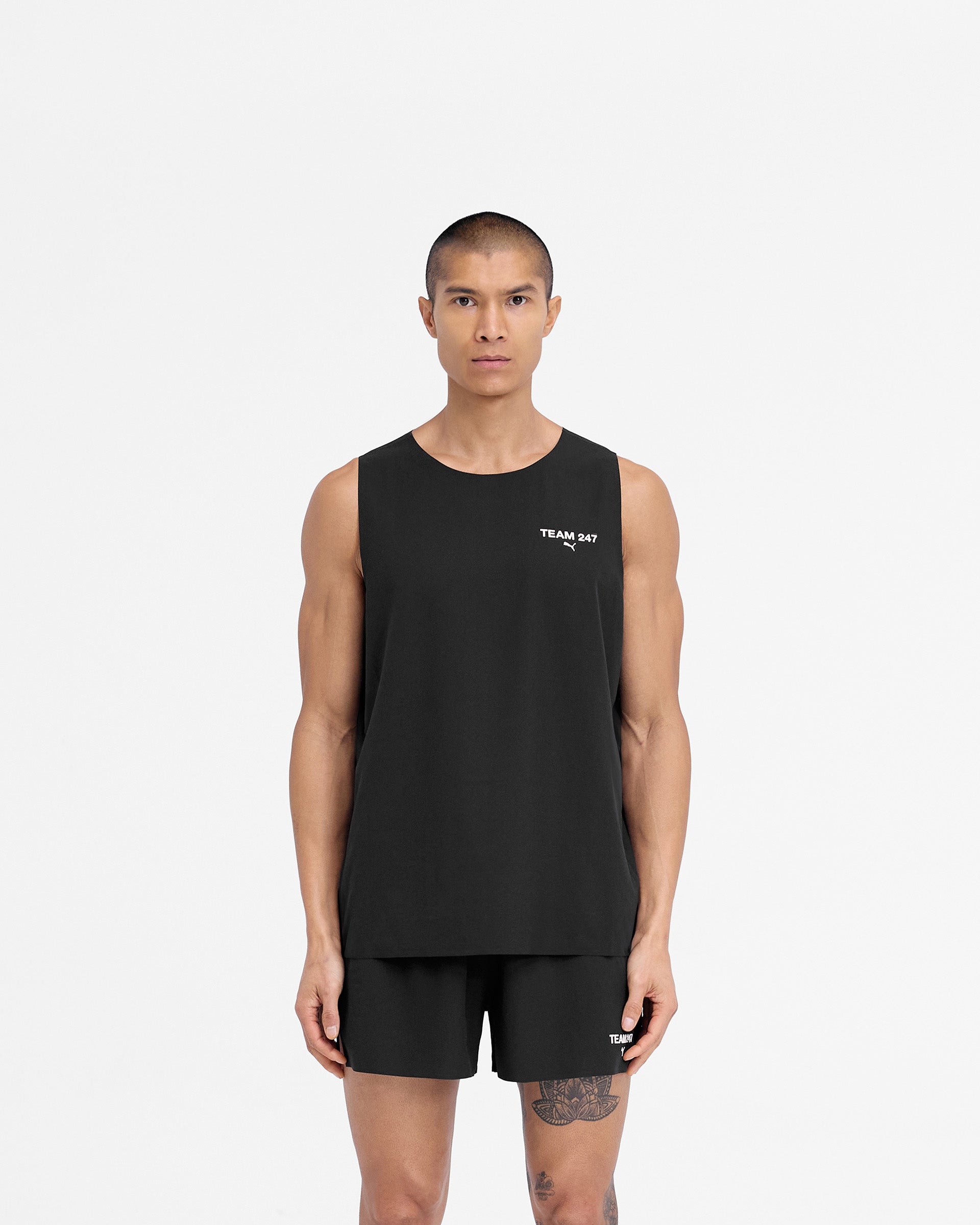 Man wearing a black oversized tank on a plain white background | 247 X Puma Oversized Tank in Black | Lightweight woven fabric T-Shirts | 247 T-Shirts | Represent Clo