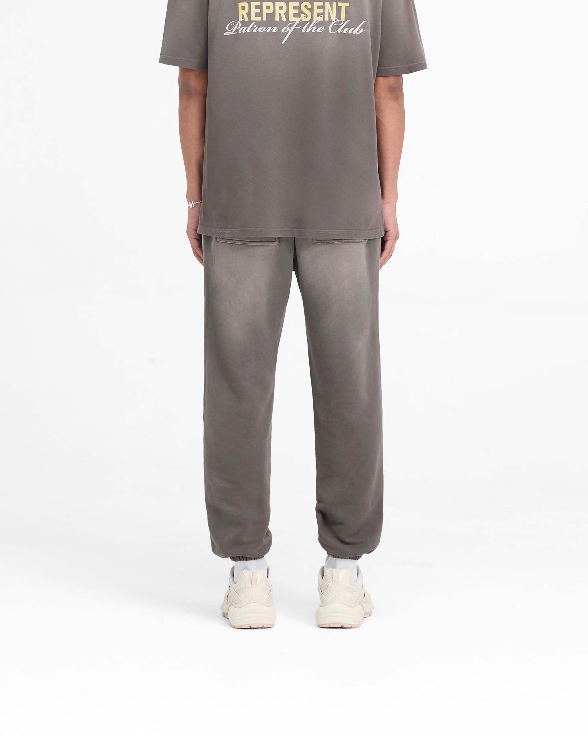Man wearing relaxed fit washed olive sweatpants on a plain white background | Patron Of The Club Sweatpant in Washed Olive | Heavyweight cotton sweatpants with elasticated waistband and cuffs | Patrons Pants | Represent Clo