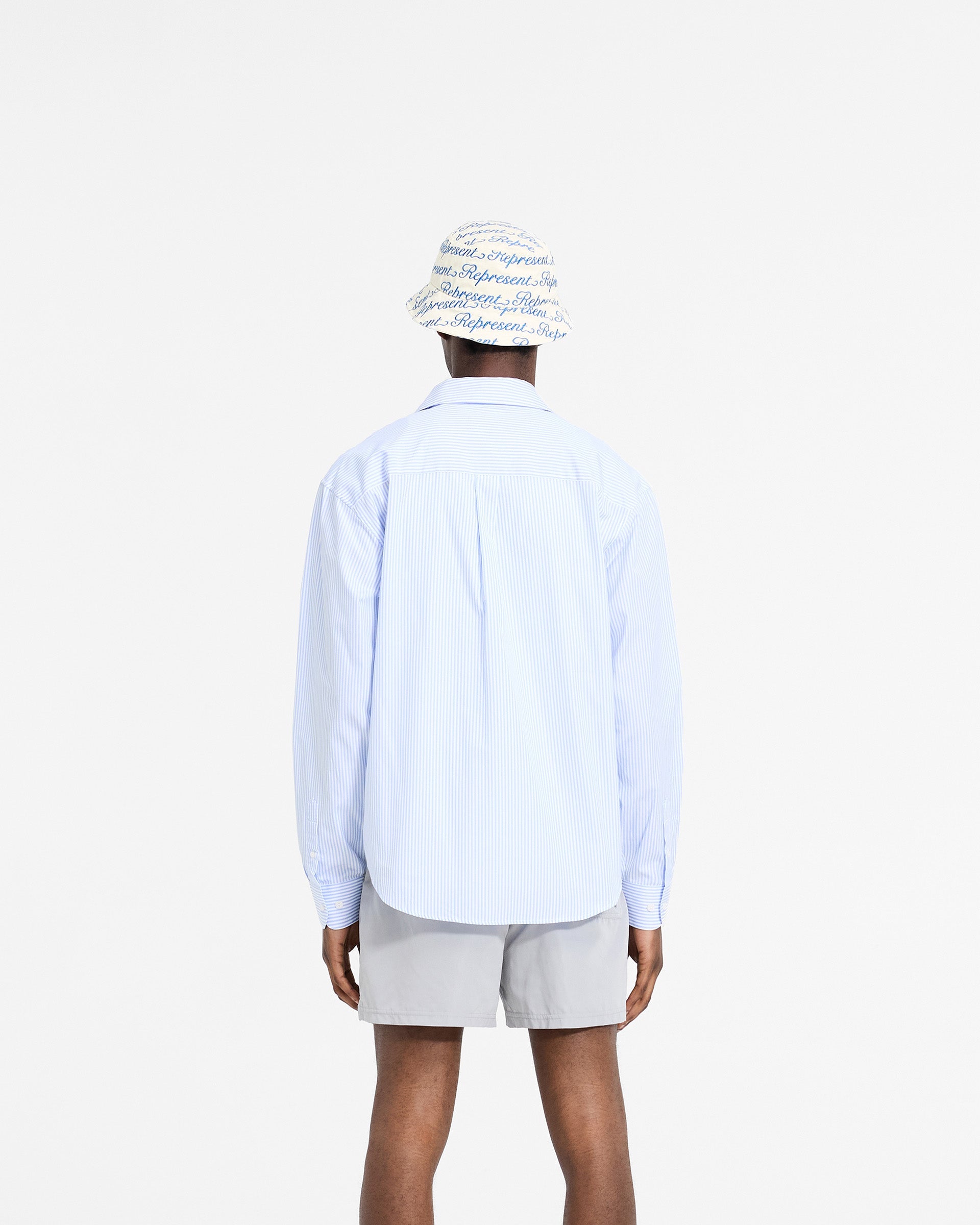 Man wearing a blue pinstripe shirt on a plain white background | Long Sleeve Pinstripe Shirt in Baby Blue | Pinstripe shirt with curved hem and chest pockets | SC24 Shirts | Represent Clo