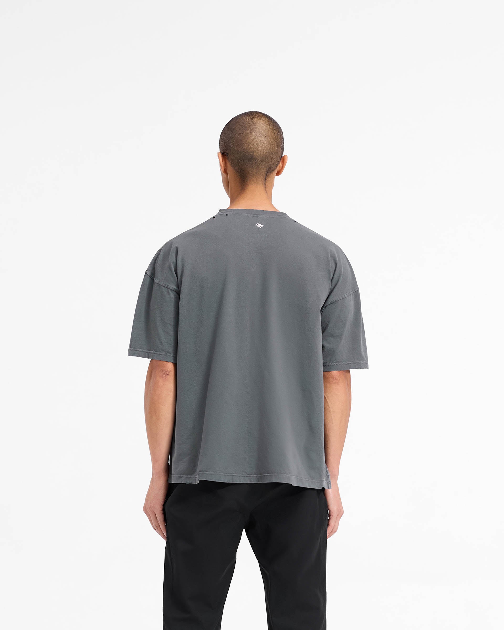 Man wearing a slightly oversized black t-shirt on a plain white background | 247 On A Mission Oversized T-Shirt in Aged Black | Lightweight jersey cotton t-shirt with embroidery and distressing details | 247 T-Shirts | Represent Clo