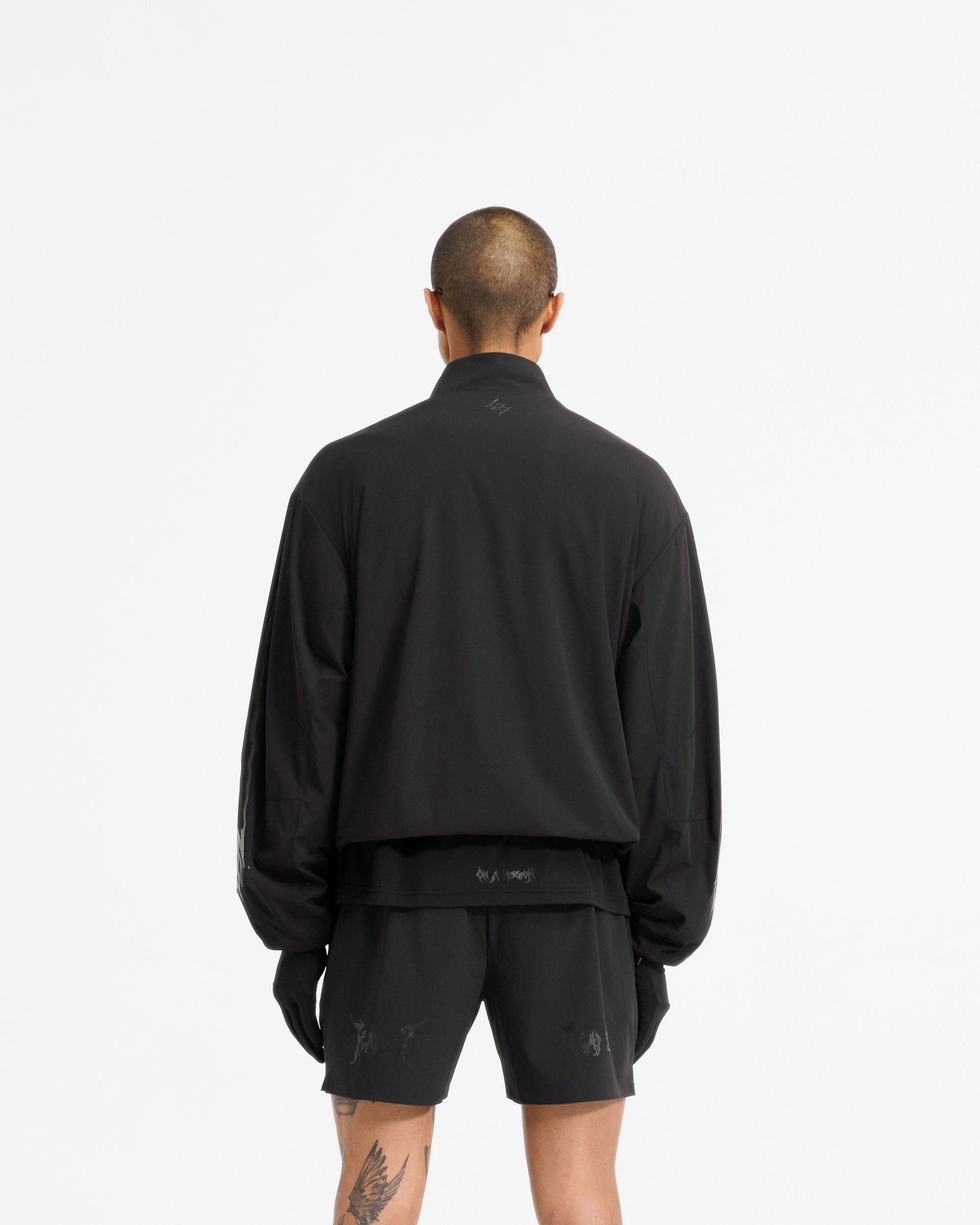 Man wearing a black track jacket on a plain white background | Team 247 X END Track Jacket in Jet Black | Track jacket with 4-way stretch nylon shell and mesh lining | 247 Outerwear | Represent Clo
