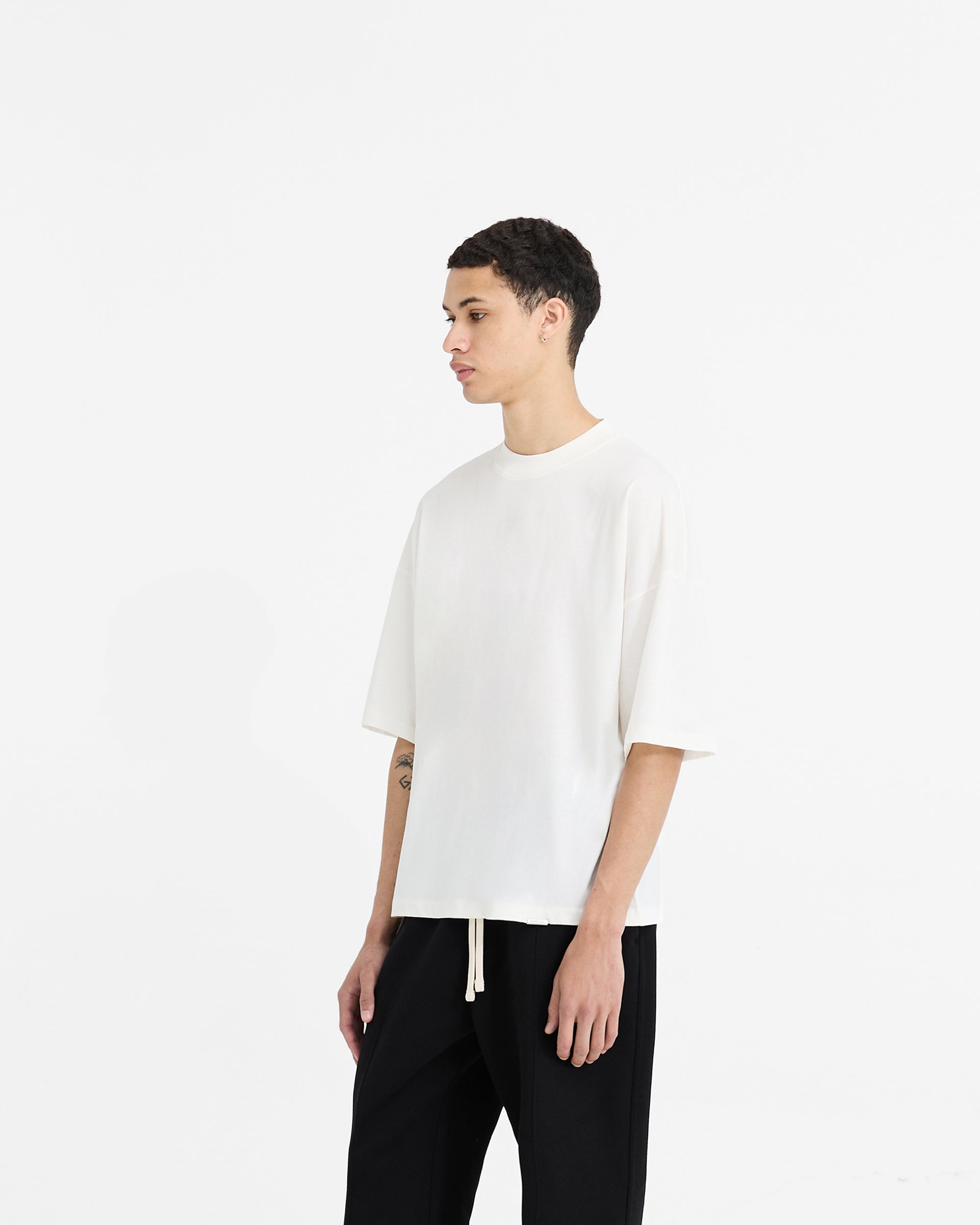 Back product image of a mens white t-shirt on a plain white background | Initial Boxy T-Shirt in Flat White | Oversized boxy cropped t-shirt with embroidered initial and metal bar logo | Initial T-Shirts | Represent Clo