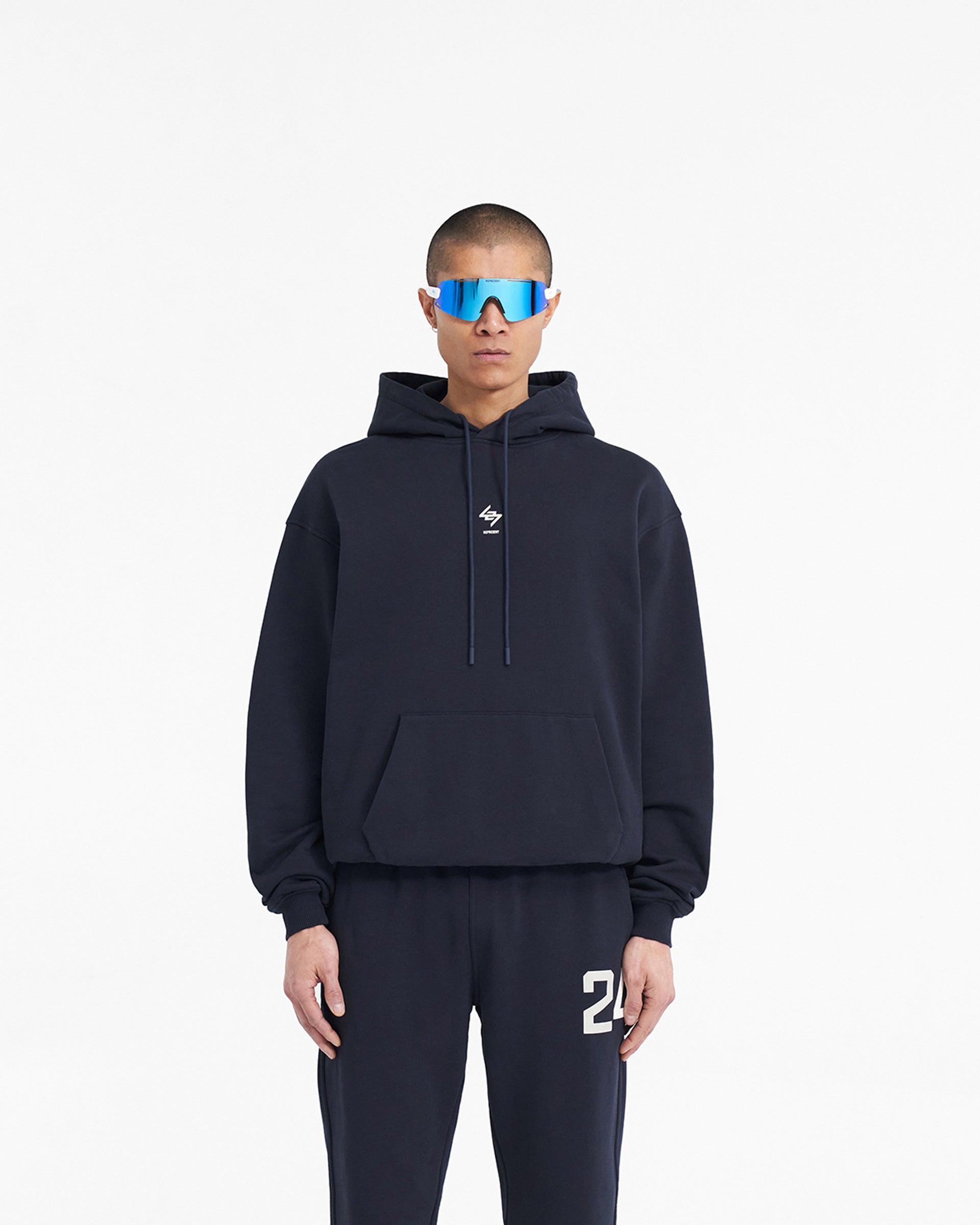 Man wearing a navy hoodie on a plain white background | 247 Oversized Hoodie in Navy | Oversized hoodie with ribbed cuffs and hem | 247 Hoodies | Represent Clo