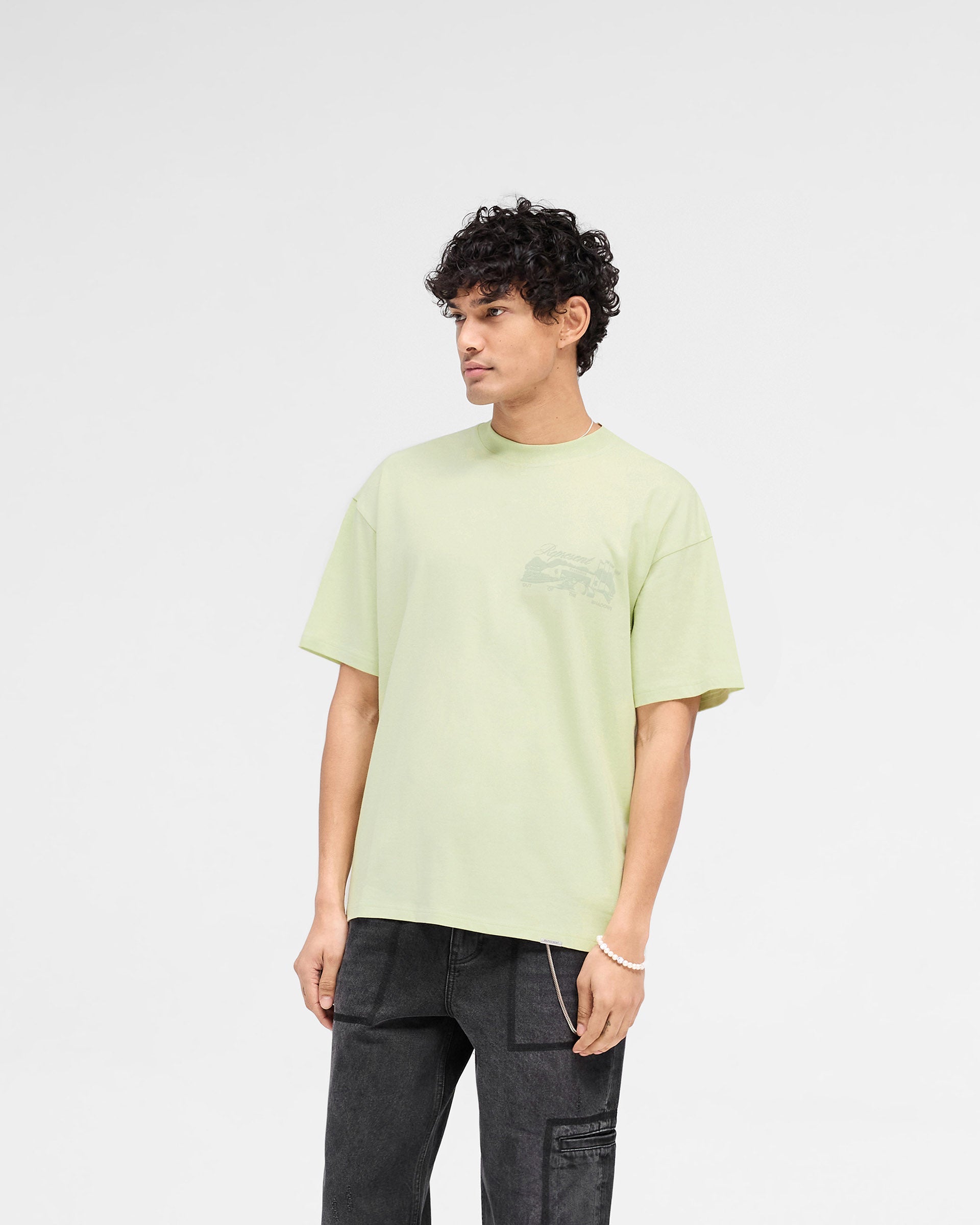 Man wearing a green t-shirt on a plain white background | Raceway T-Shirt in Matcha | Slightly oversized t-shirt with puff print graphic | SS25 T-Shirts | Represent Clo