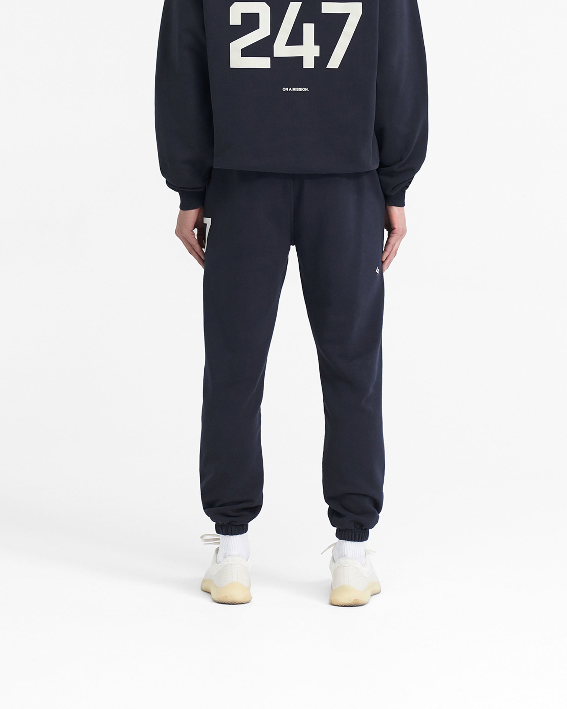 Man wearing navy sweatpants on a plain white background | 247 Sweatpant in Navy | Training joggers with elasticated cuffs and drawcord waistband | 247 Pants | Represent Clo