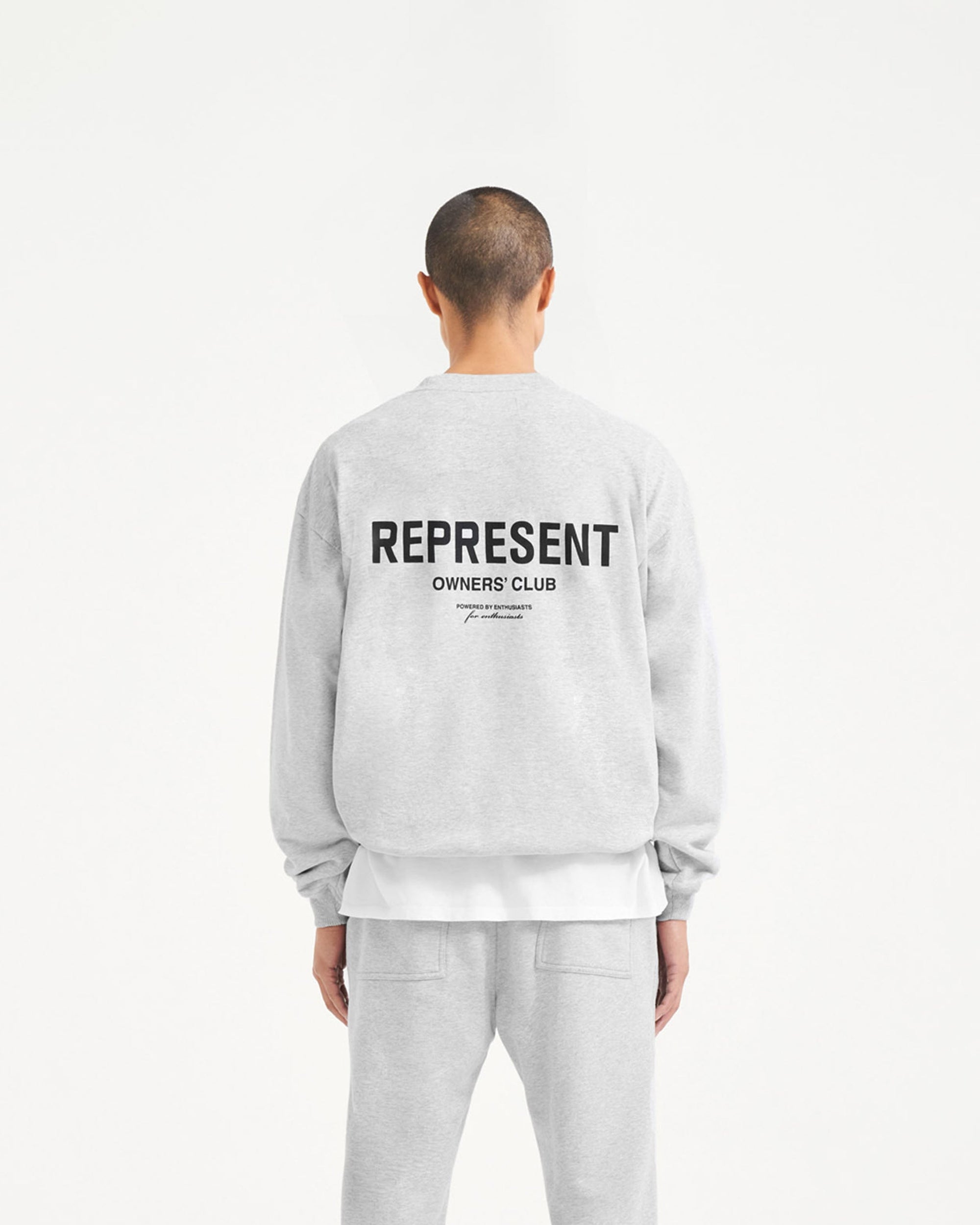 Man wearing an ash grey sweater on a plain white background | Represent Owners Club Sweater in Ash Grey | Crewneck sweater with oversized fit and ribbed trims | Owners Club Sweaters | Represent Clo