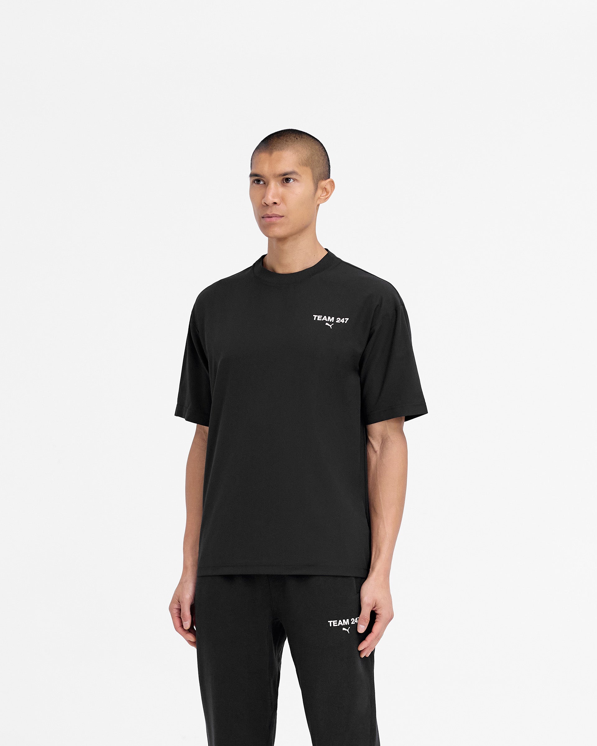 Man wearing a black oversized t-shirt on a plain white background | 247 X Puma Oversized T-Shirt in Black | Oversized t-shirt with ultraweave fabric and 3D branding | 247 T-Shirts | Represent Clo