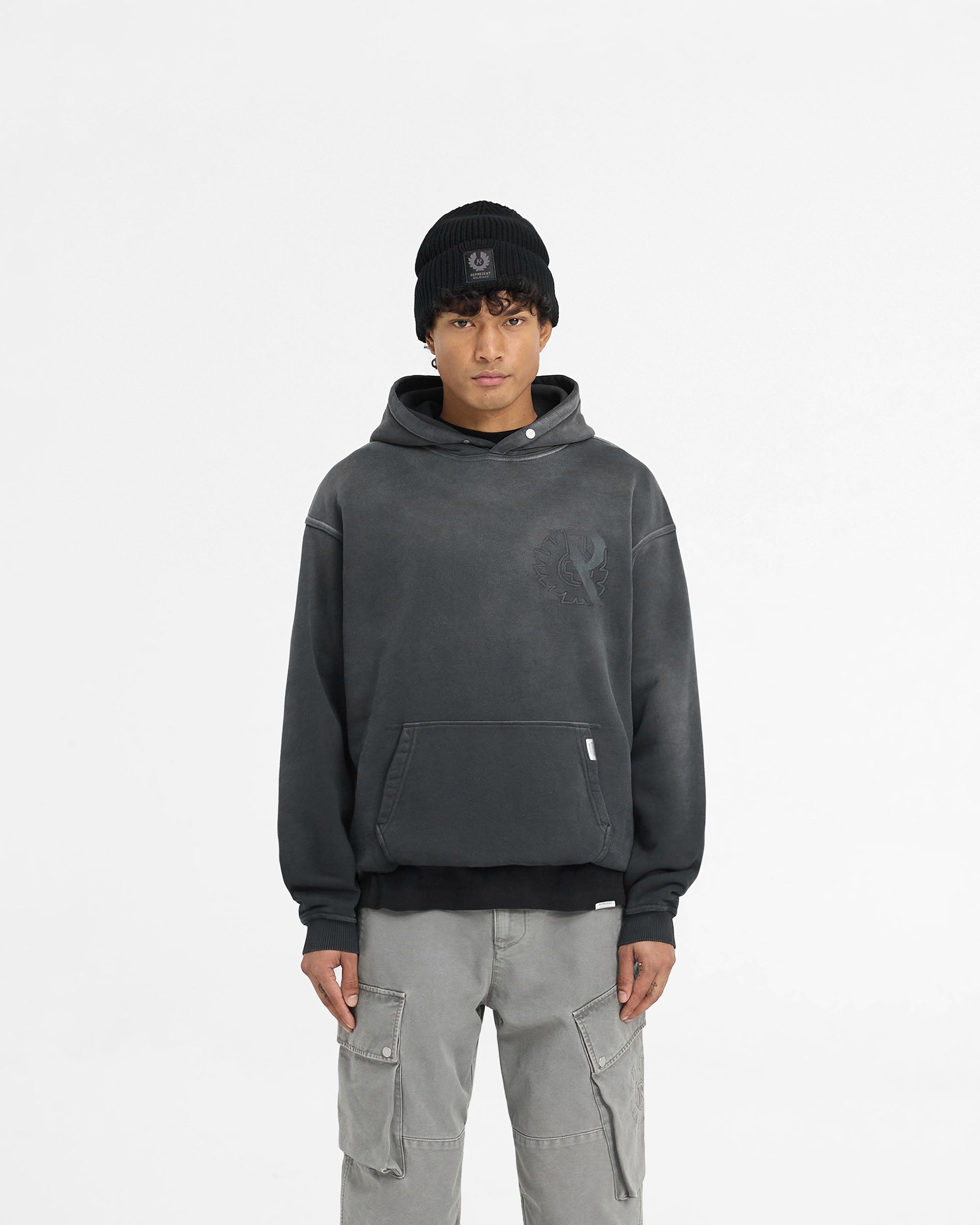 Man wearing a black oversized hoodie on a plain white background | Represent X Belstaff Outline Phoenix Hoodie in Shadow | Oversized heavyweight hoodie with logos | Exclusives Hoodies | Represent Clo