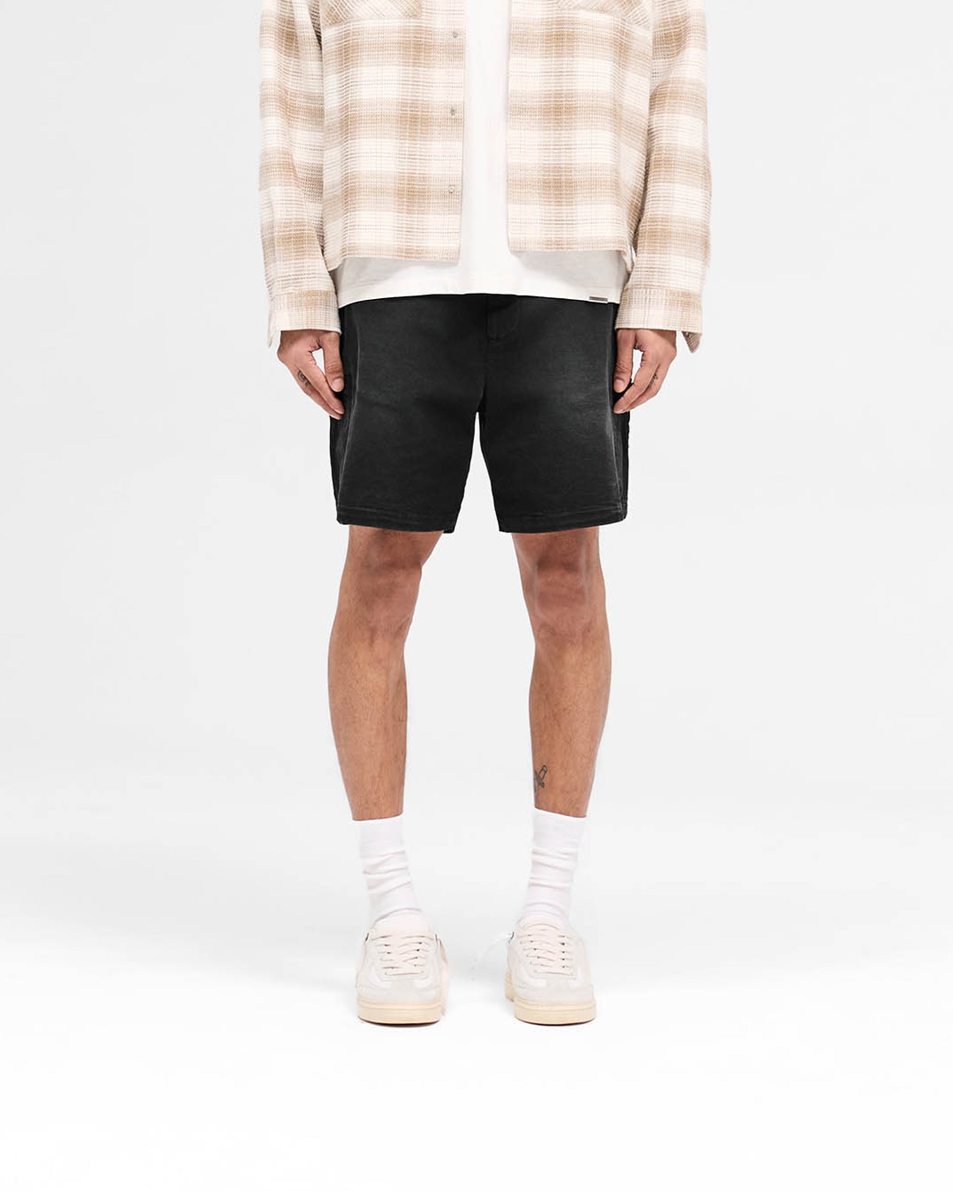 Man wearing mens black cargo shorts on a plain white background | Season Cargo Short in Jet Black | Cargo shorts with welt pockets and YKK fly | SS25 Shorts | Represent Clo
