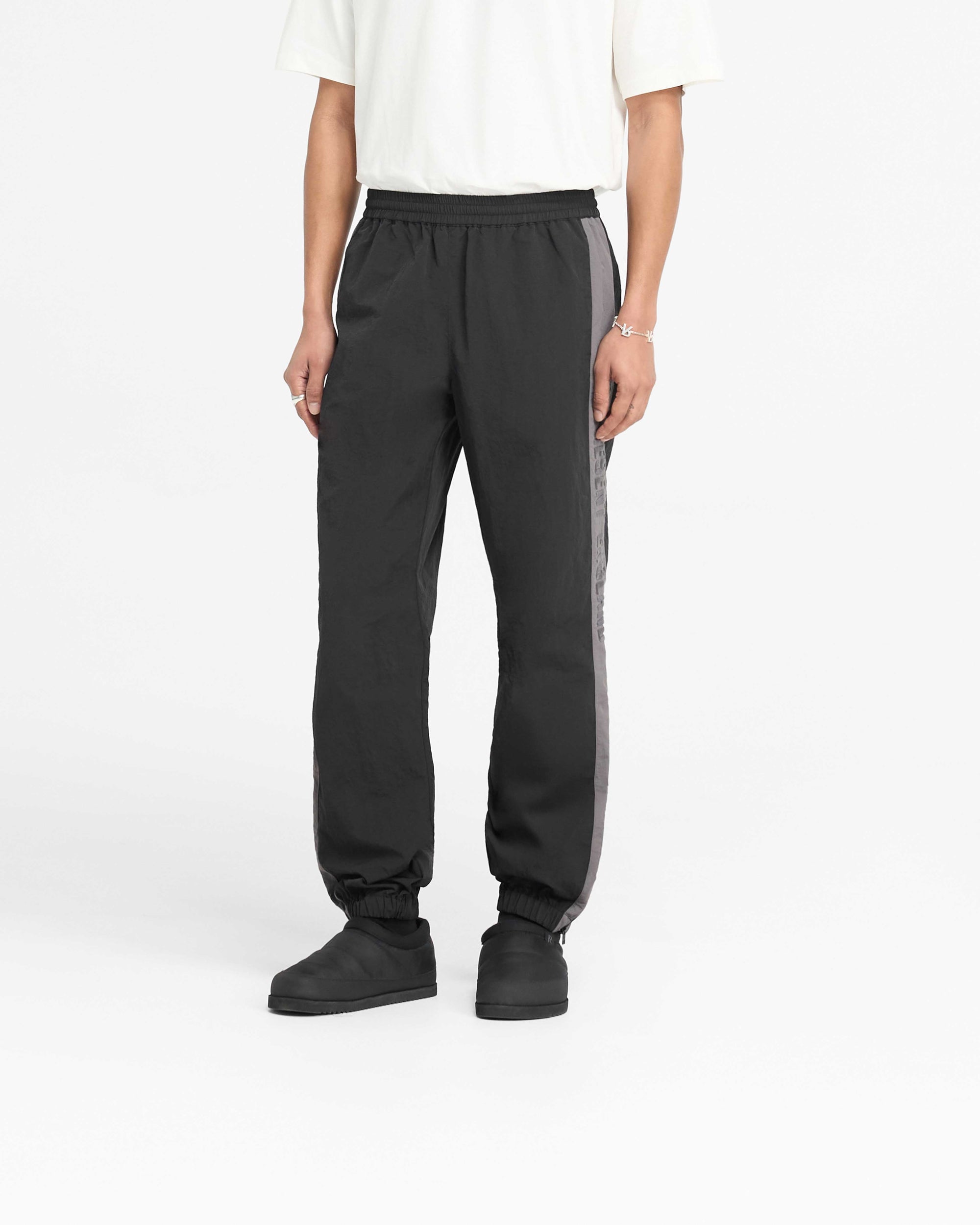 Back product image of mens black nylon pants on a plain white background | Nylon Track Pant in Black | Pants with elasticated cuff and hem zip | PRE SS25 Pants | Represent Clo