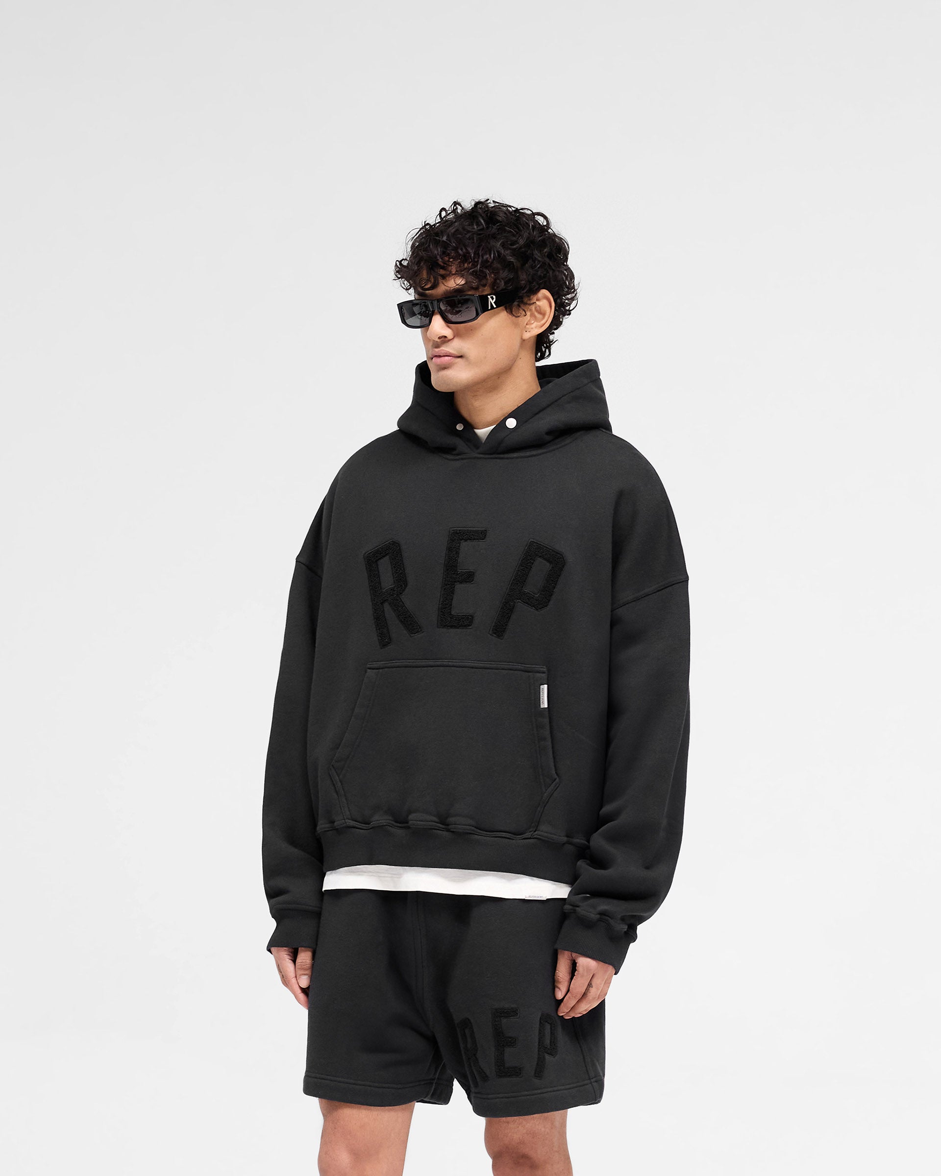 Back product image of a mens black hoodie on a plain white background | Rep Applique Hoodie in Off Black | Boxy fit hoodie with textured Rep applique | SS25 Hoodies | Represent Clo