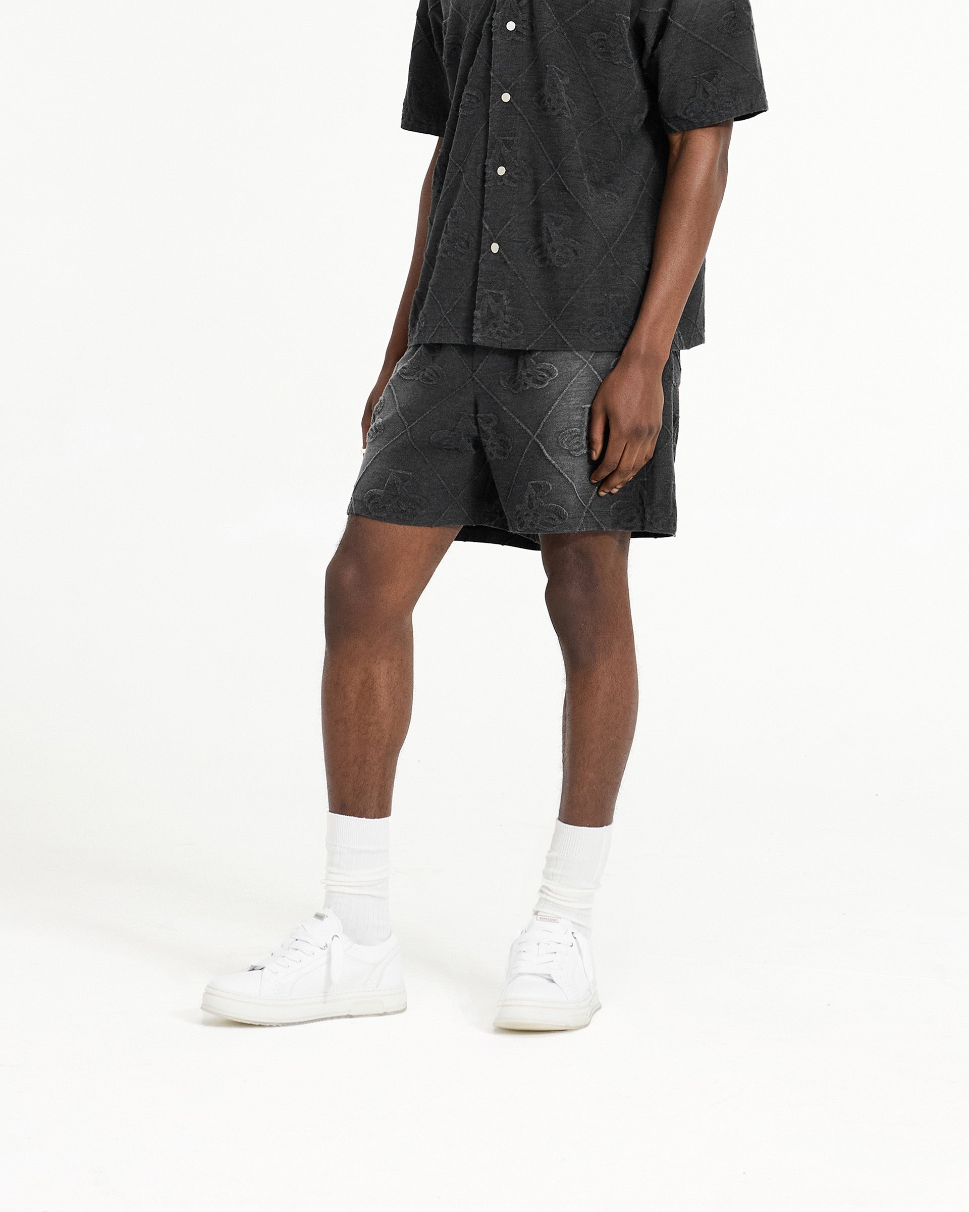 Man wearing black shorts on a plain white background | Towelling Short in Jet Black | Relaxed fit shorts with elasticated waistband | SC24 Shorts | Represent Clo