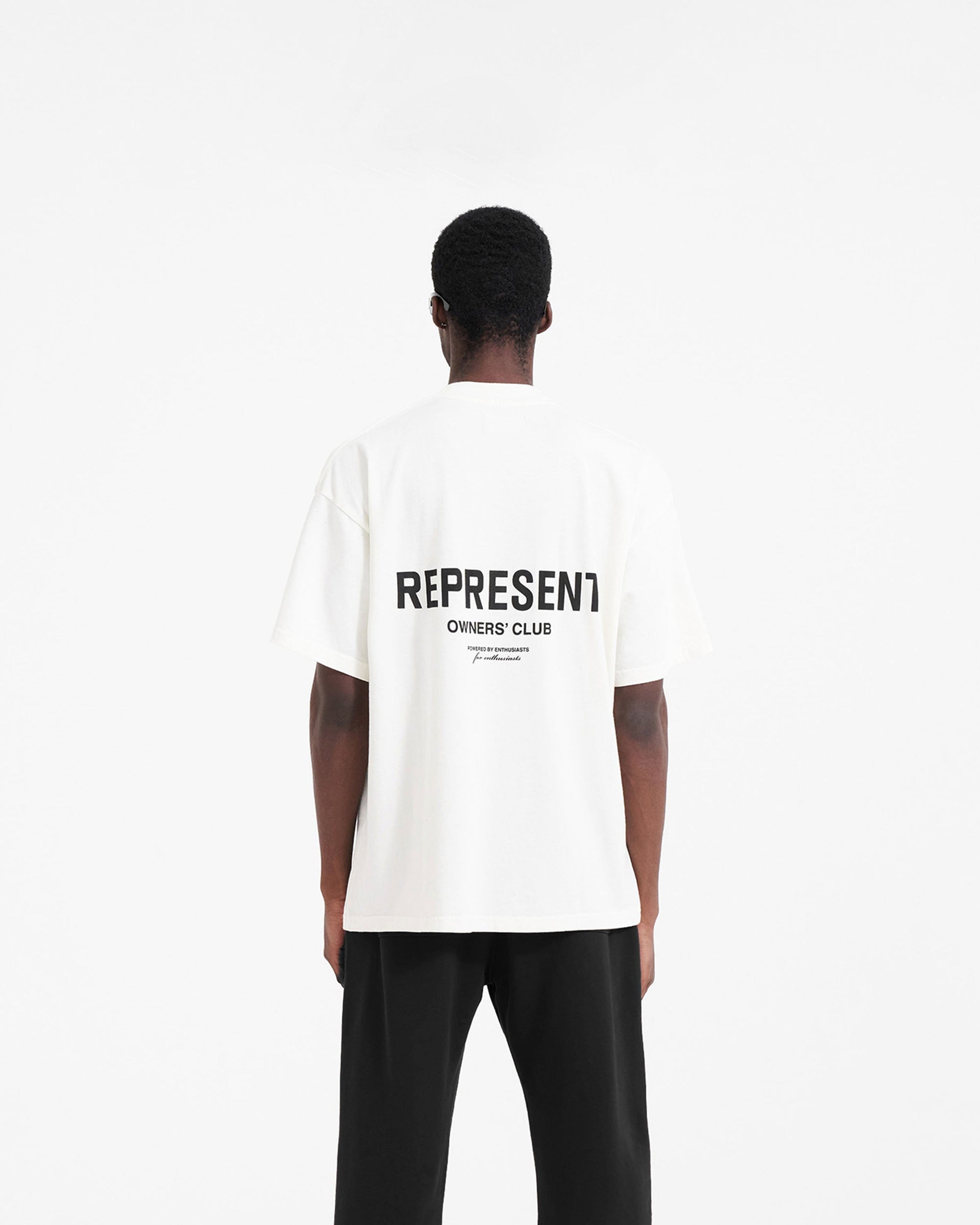 Man wearing black sweatpants on a plain white background | Represent Owners Club Sweatpant in Black | Sweatpants with elasticated waistband and logo print | Owners Club Pants | Represent Clo