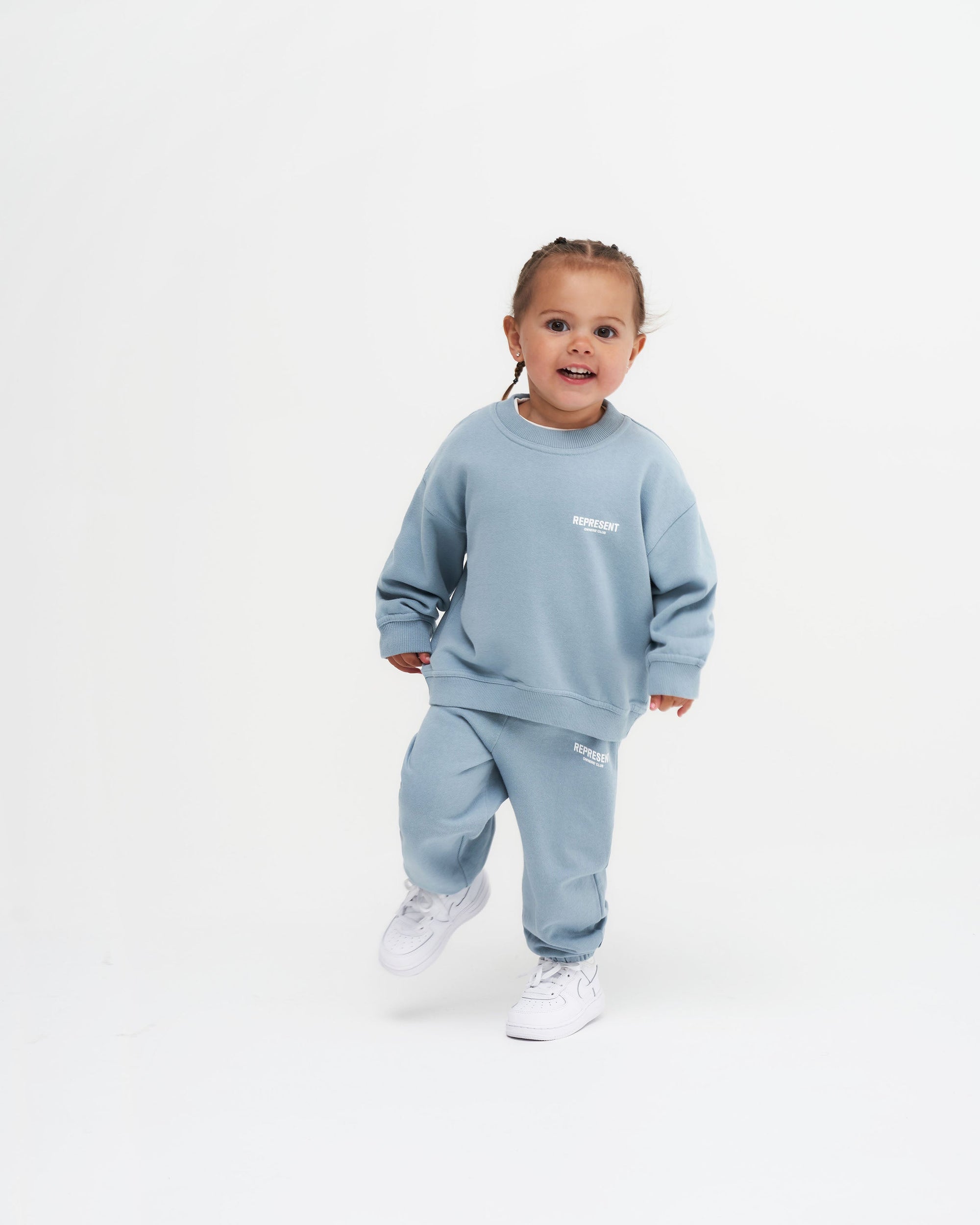 Back product image of kids blue sweatpants on a plain white background | Represent Mini Owners Club Sweatpants in Powder Blue | Kids sweatpants with elasticated waistband and Owners' Club logo | Owners Club Pants | Represent Clo