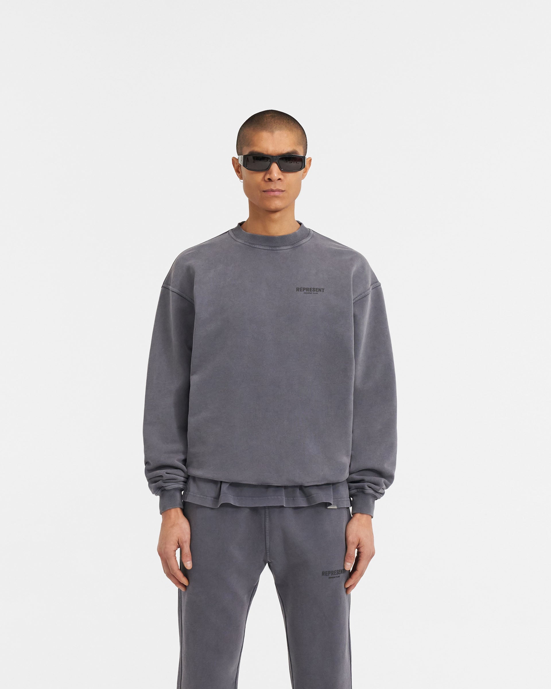 Man wearing a grey sweater on a plain white background | Represent Owners Club Sweater in Storm | Oversized fit sweater with high build print | Owners Club Sweaters | Represent Clo
