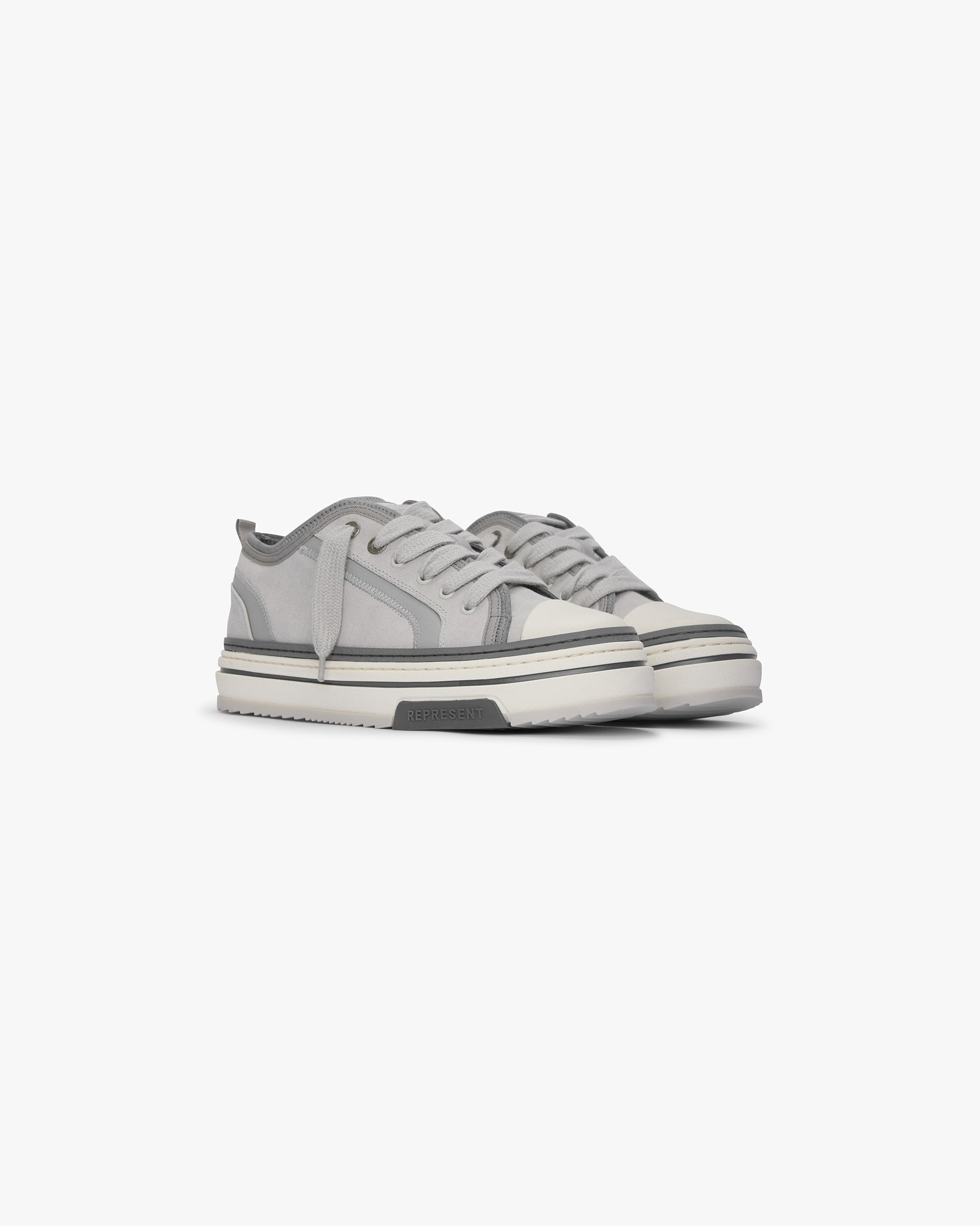 Product image of mens grey sneakers on a plain white background | HTN X Low in Warm Grey | Low top sneakers with canvas upper and chunky rubber outsole | SS24 Footwear | Represent Clo