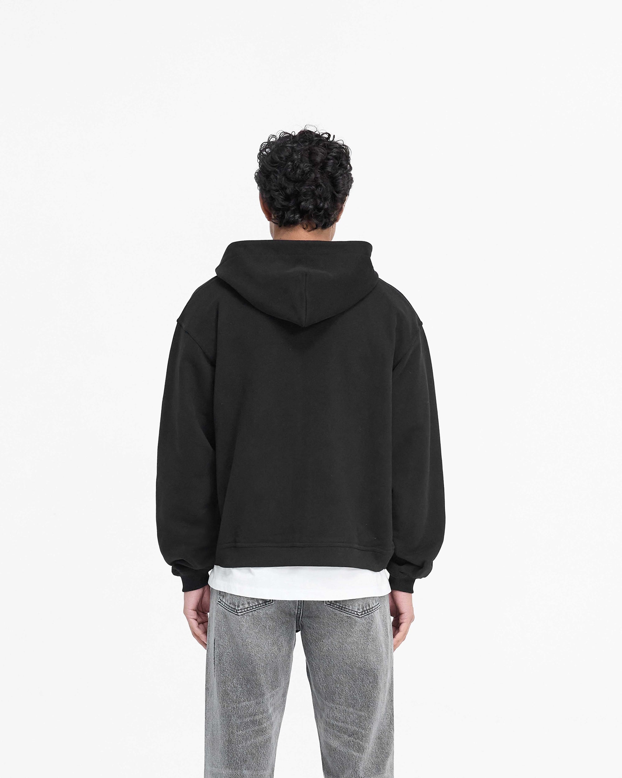 Man wearing a black zip hoodie on a plain white background | Script Logo Zip Hoodie in Black | Oversized cotton hoodie with high build embroidery | PRE SS25 Hoodies | Represent Clo