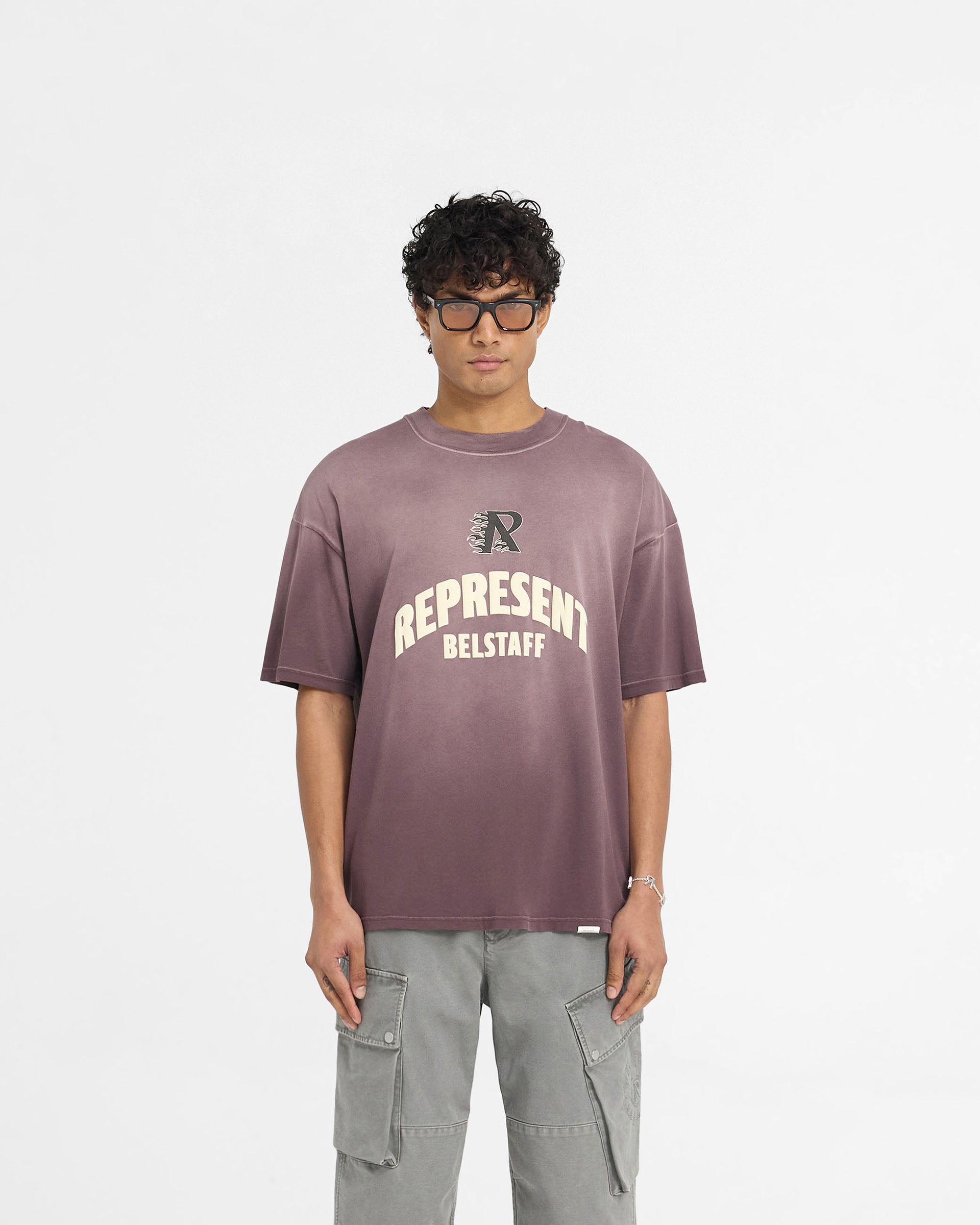 Man wearing an oversized plum t-shirt on a plain white background | Represent X Belstaff Flame Phoenix T-Shirt in Plum | Medium weight oversized t-shirt with stylised initial and Phoenix logos | Exclusives T-Shirts | Represent Clo