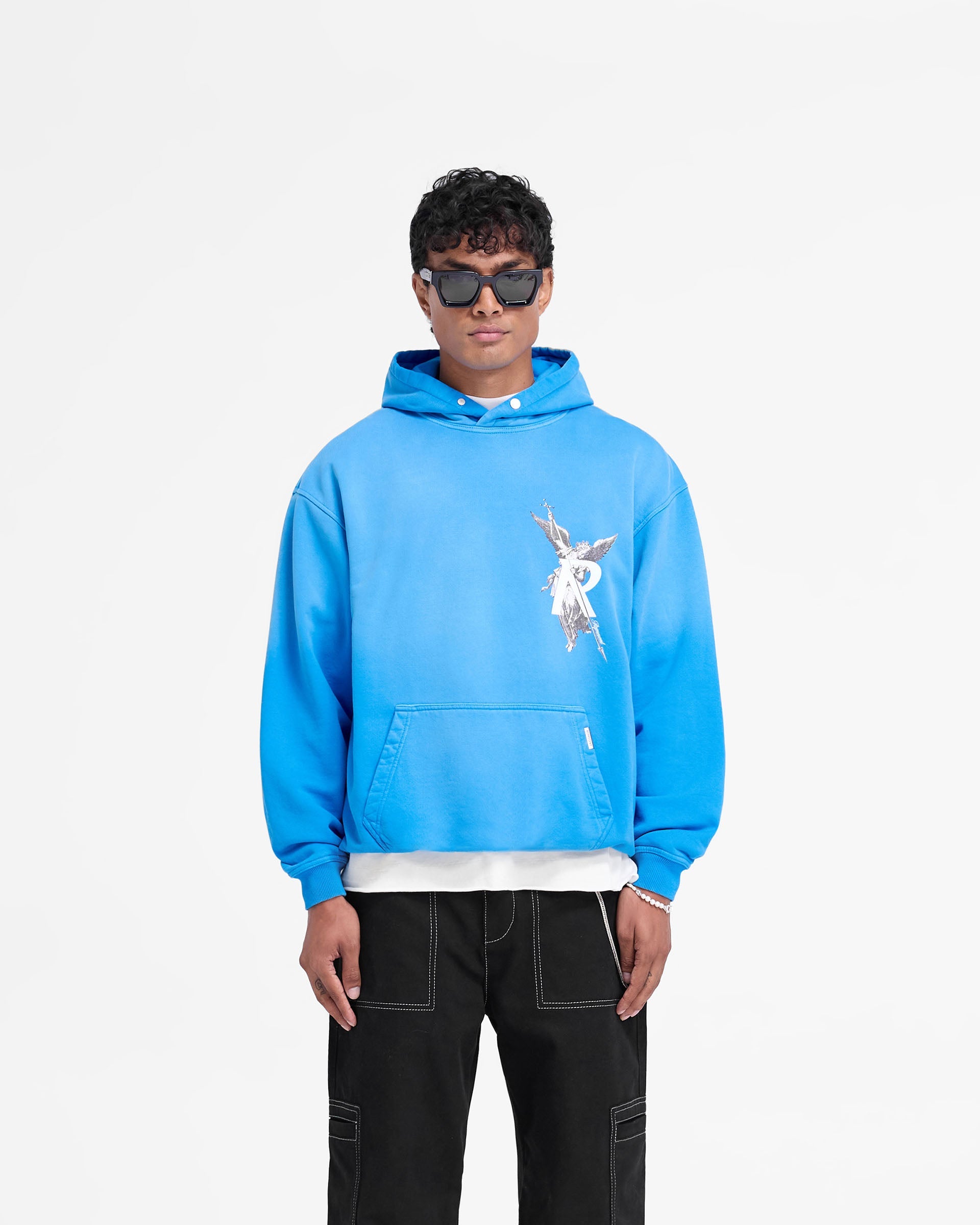 Man wearing a blue hoodie on a plain white background | Archangel Hoodie in Electric Blue | Slightly oversized hoodie with high density graphic | FW24 Hoodies | Represent Clo