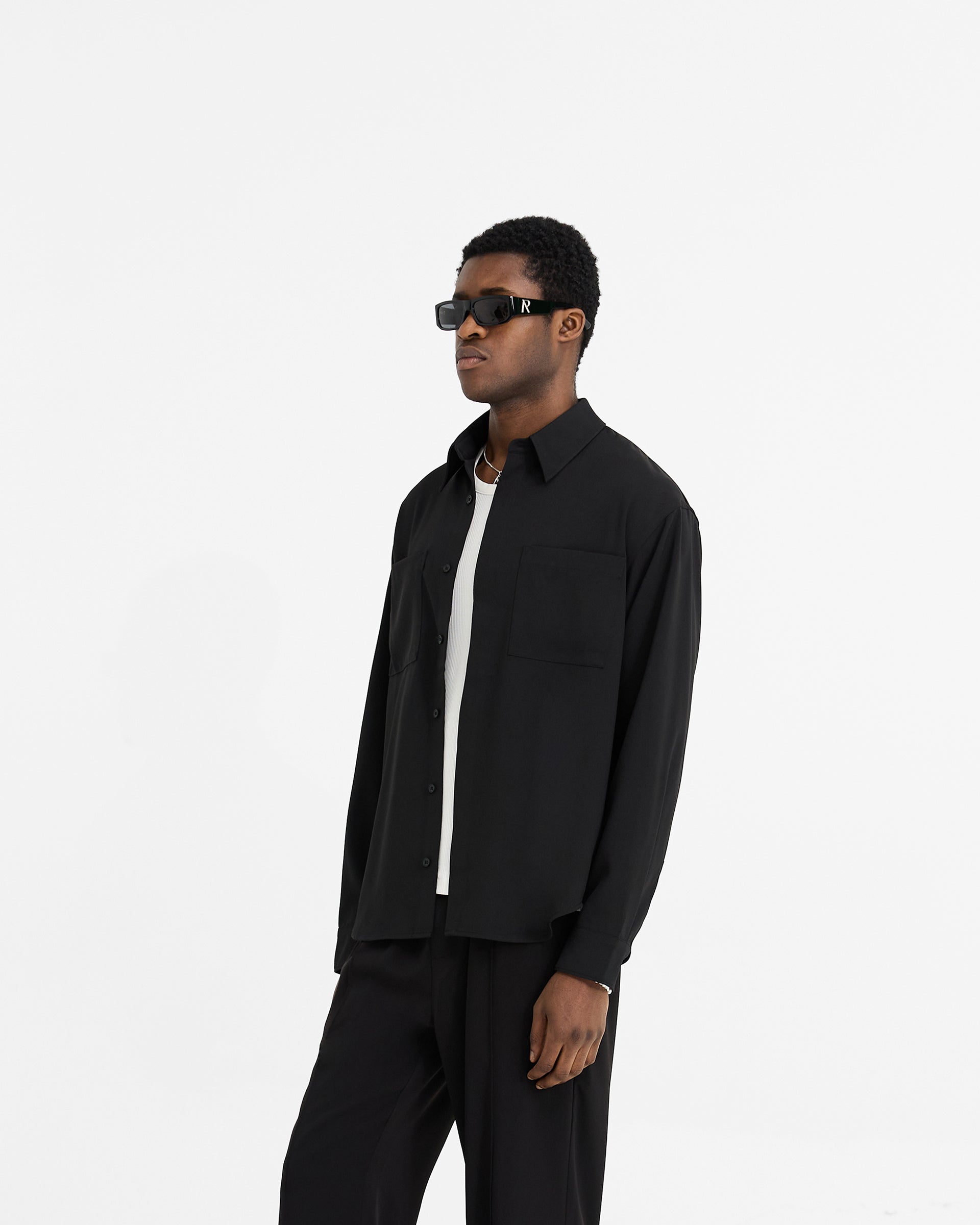 Man wearing a black shirt on a plain white background | Initial Shirt in Black | Oversized shirt with chest pockets and concealed placket | Initial Shirts | Represent Clo