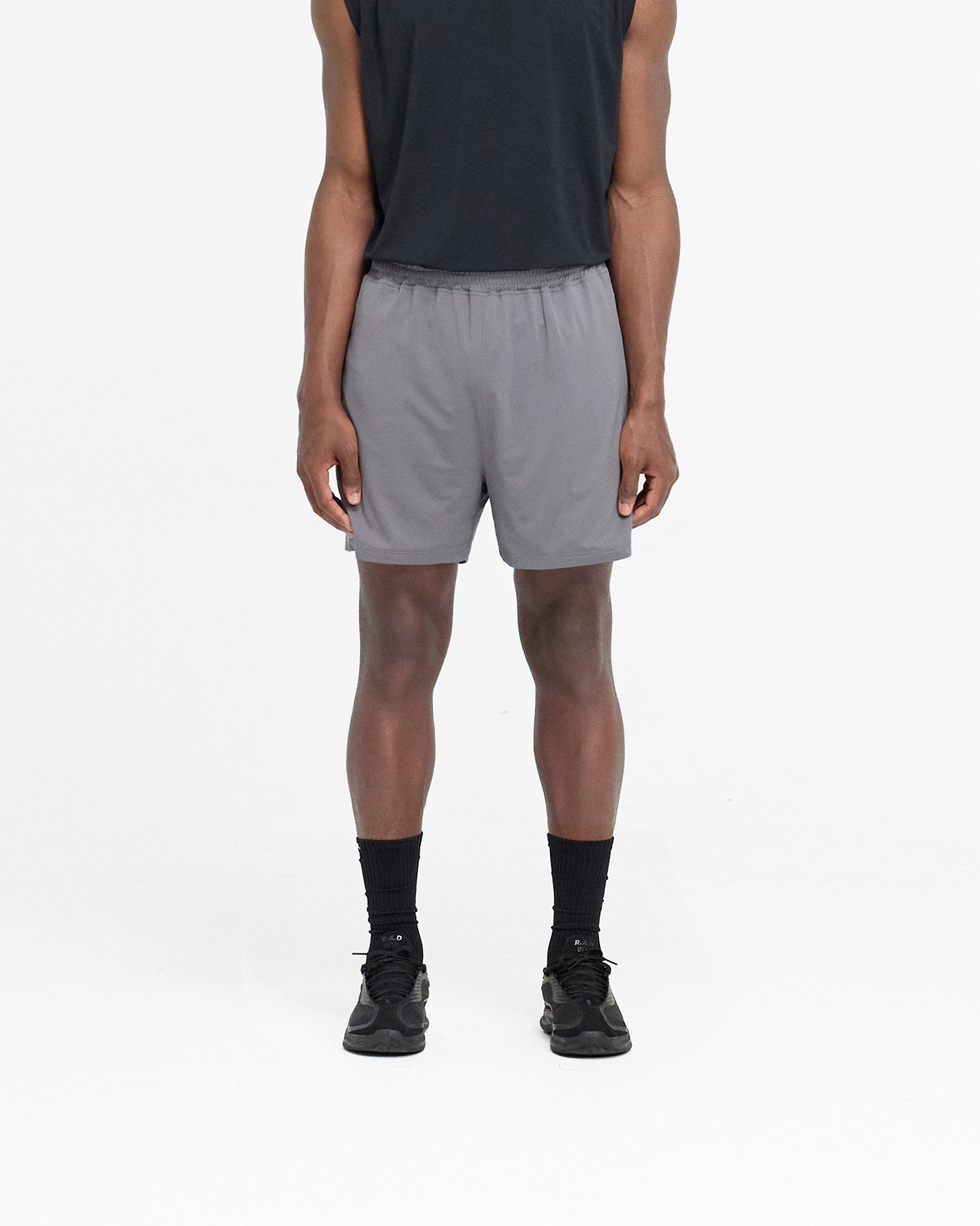 Man wearing oversized grey mesh shorts on a plain white background | 247 Mesh Shorts in Pewter | Training shorts with zip pockets and internal drawcord | 247 Shorts | Represent Clo